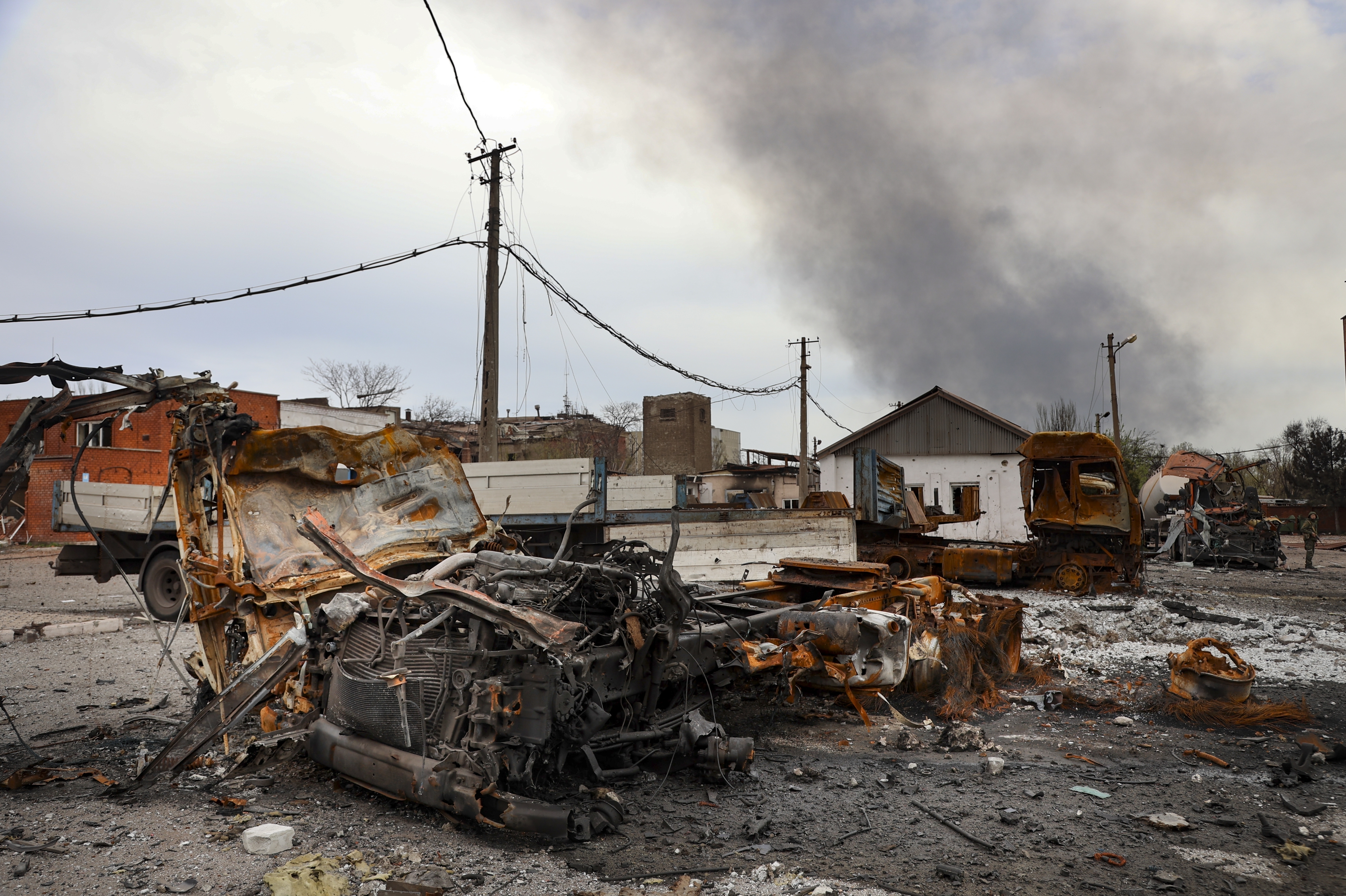 Burned vehicles at the destroyed part of the Ilyich Iron and Steel Works Metallurgical Plant, as smoke rises from the Metallurgical Combine Azovstal during heavy fighting, in an area controlled by Russian-backed separatist forces in Mariupol