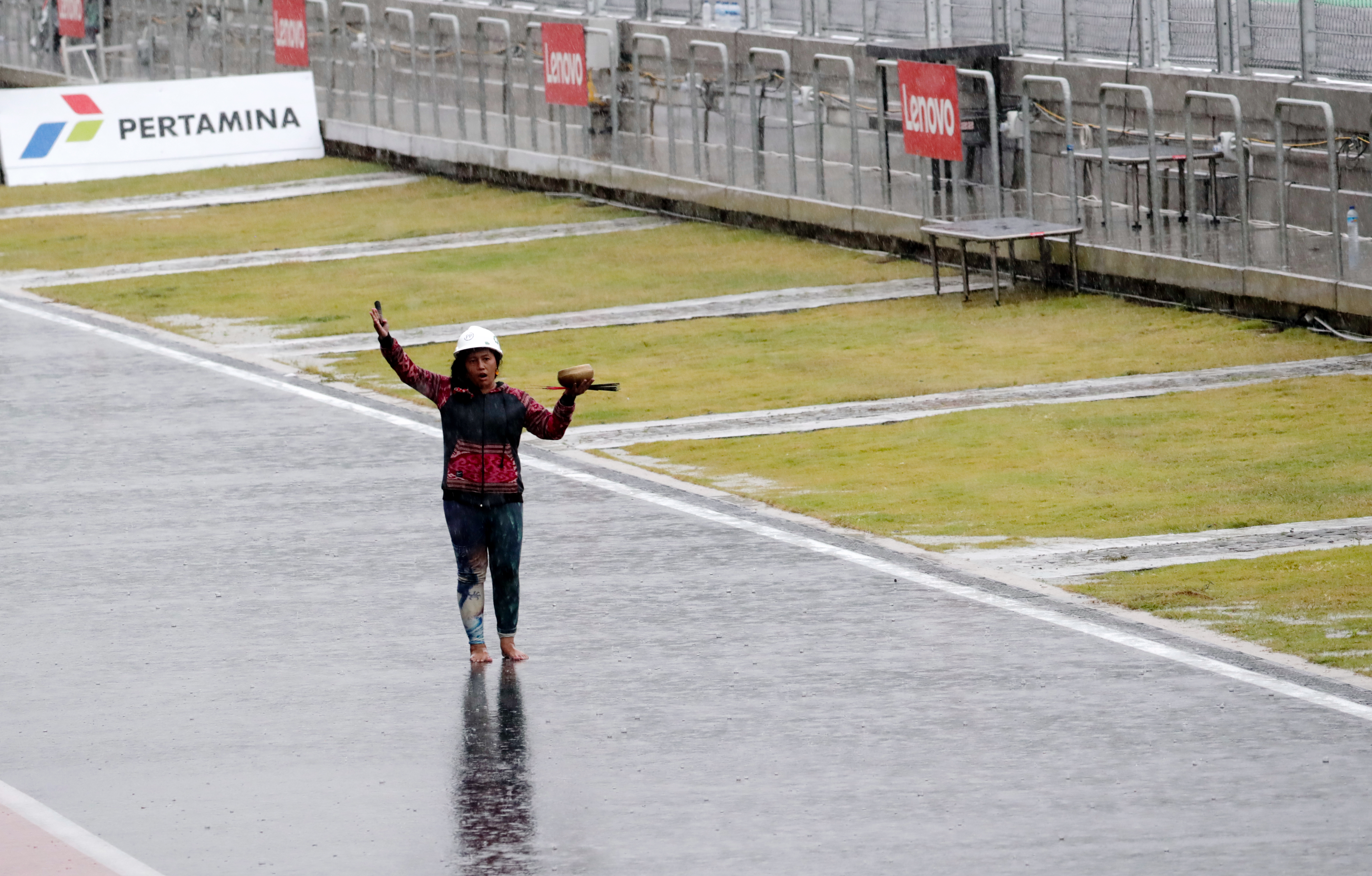 Rara Istiati Wulandar takes to the circuit barefoot during a thunderstorm in an attempt to move the rain away 