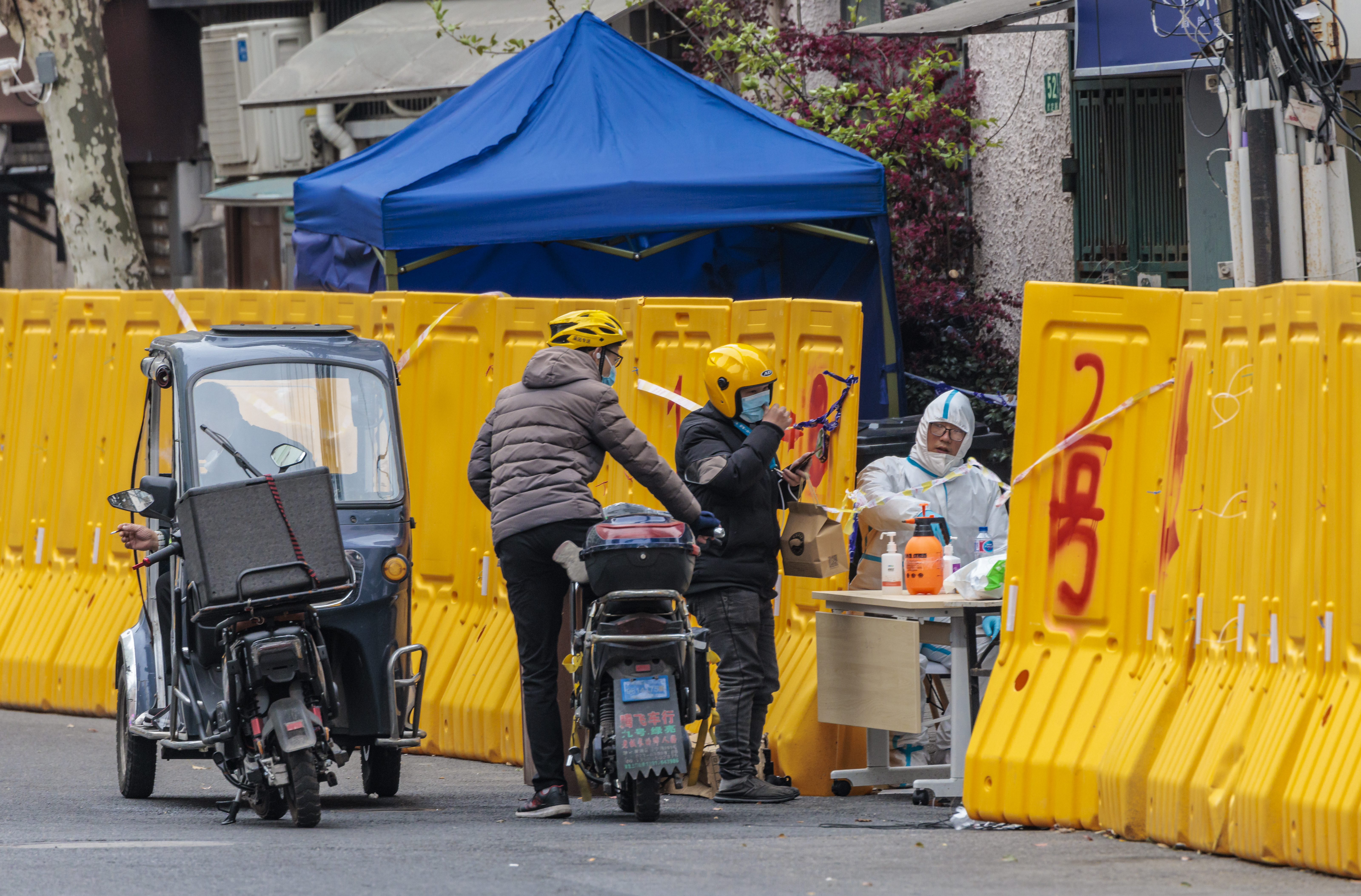People deliver packages of food and essentials to a neighbourhood sealed off behind high yellow temporary walls