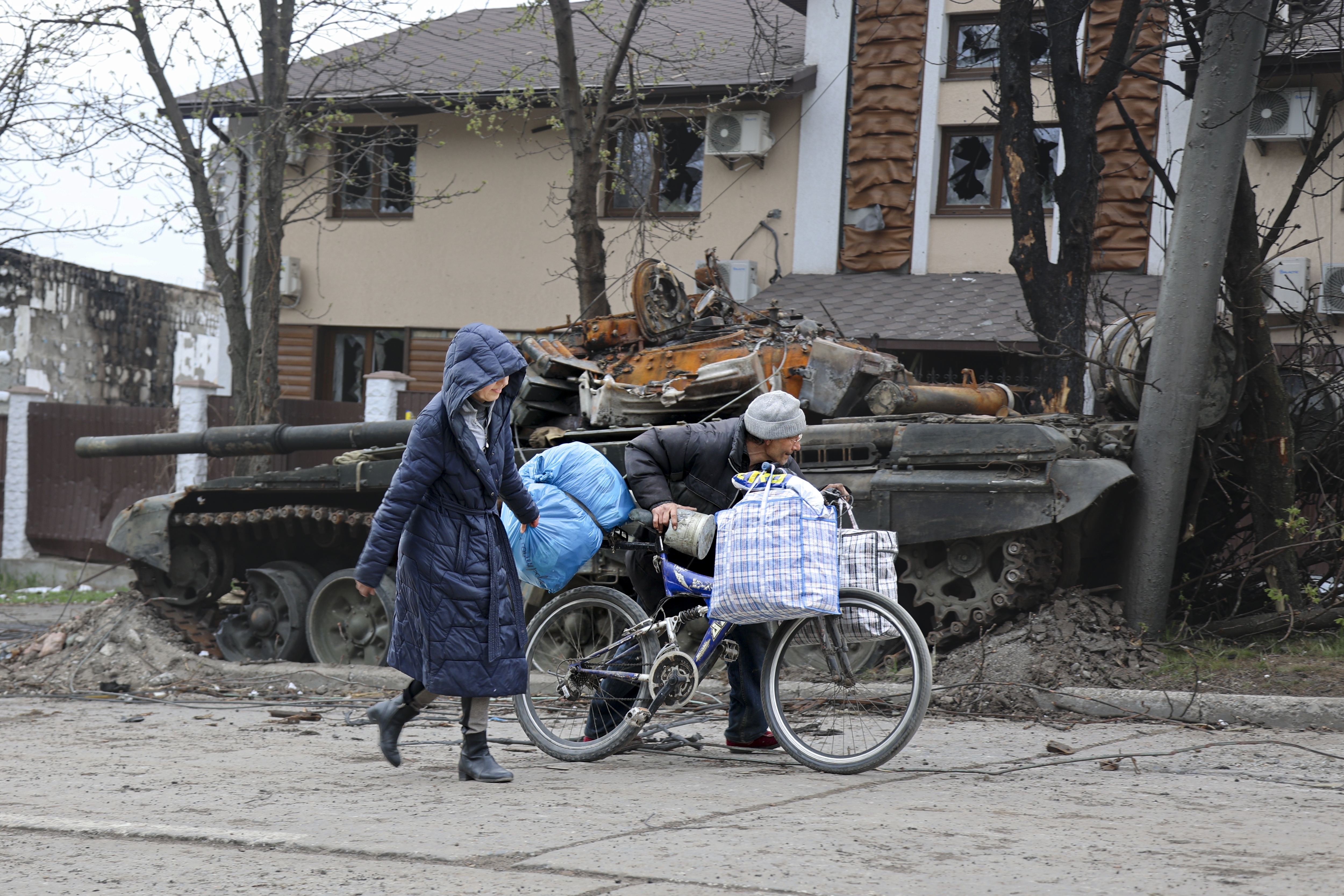 Local civilians walk past a tank destroyed during heavy fighting in an area controlled by Russian-backed separatist forces in Mariupol.