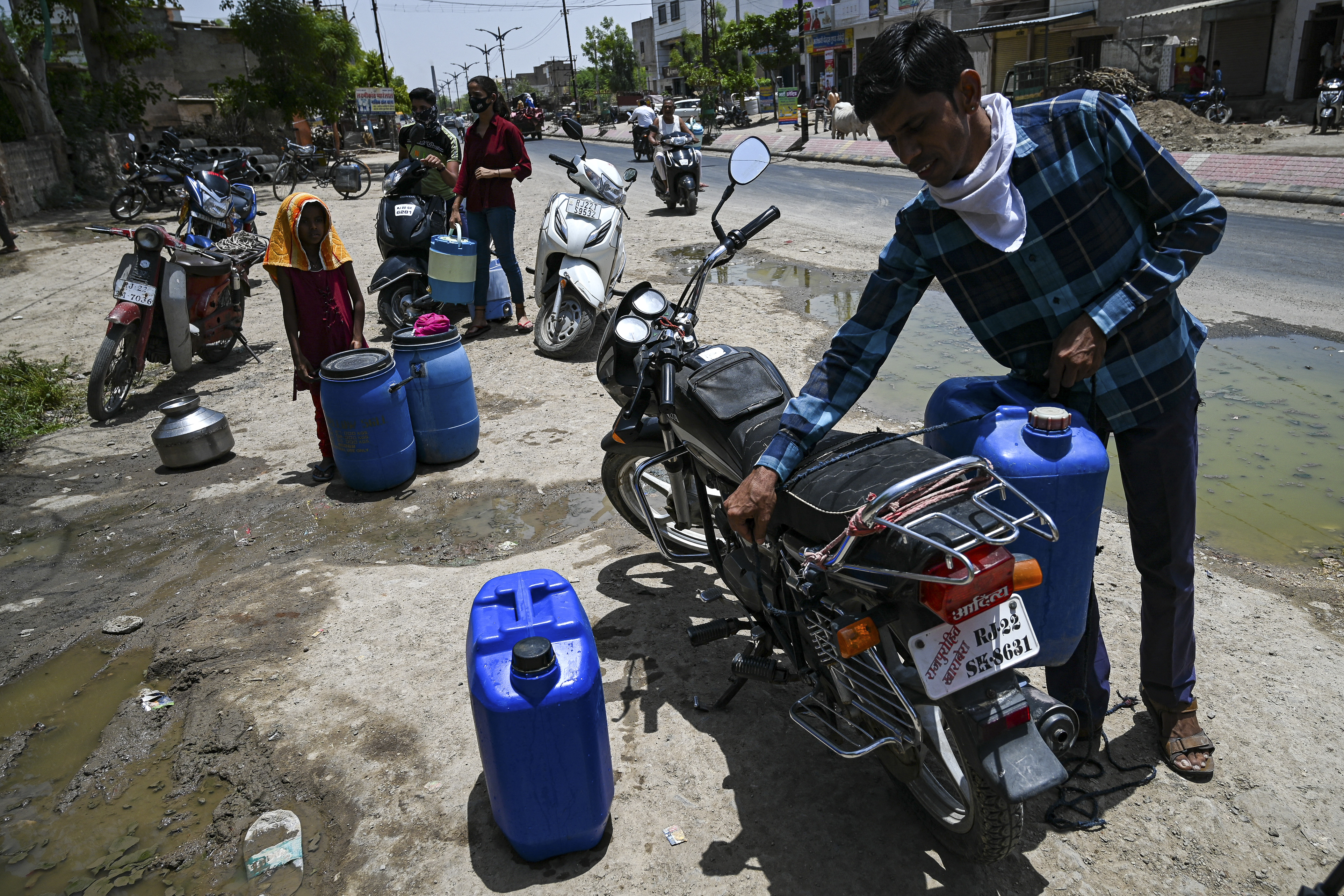 People waiting to refill their containers with tap water supplied by the government on a hot summer day in Pali.
