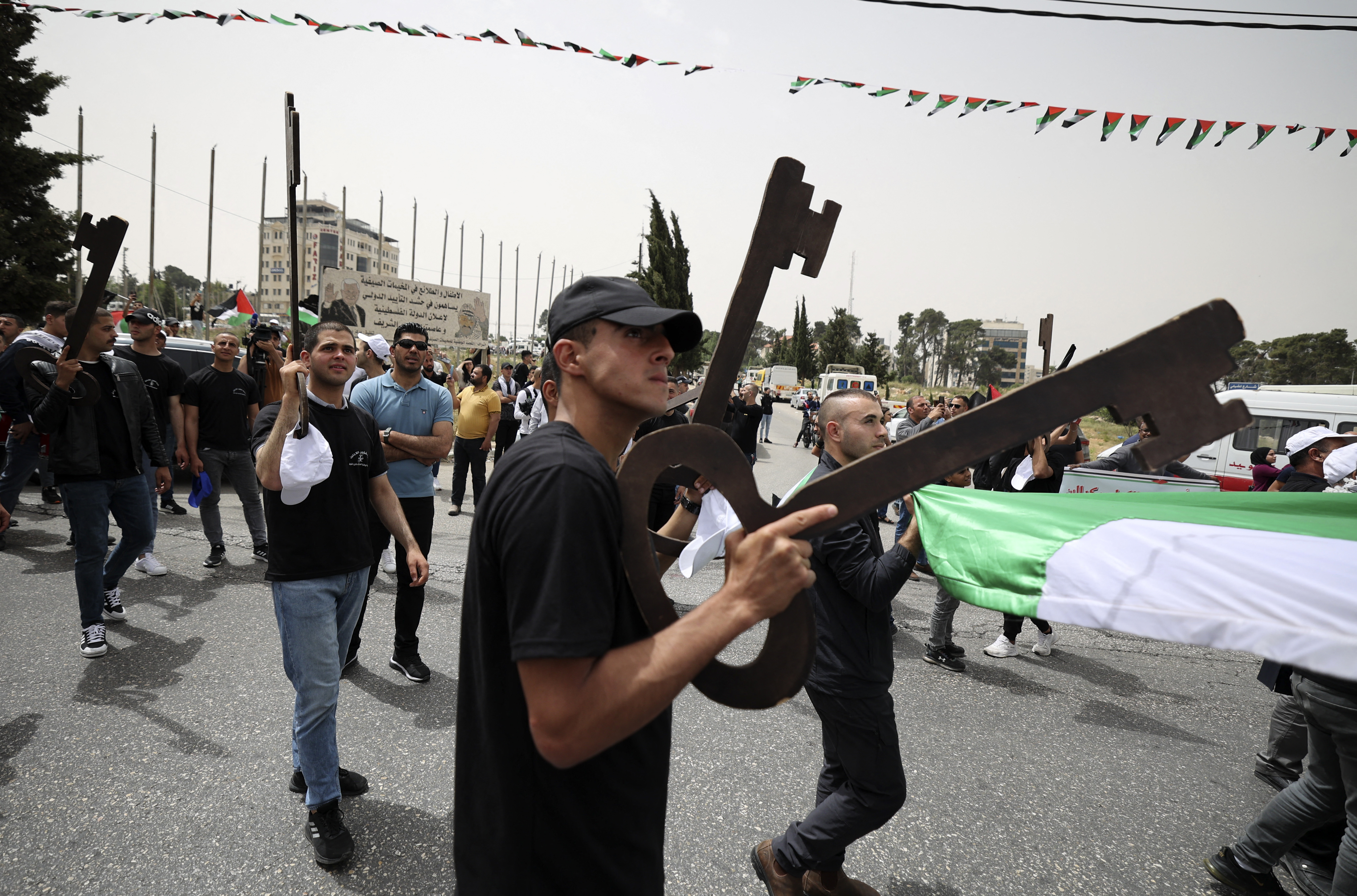 Palestinian wave national flags as they march in a rally marking the 74th anniversary of the "Nakba" or "catastrophe"