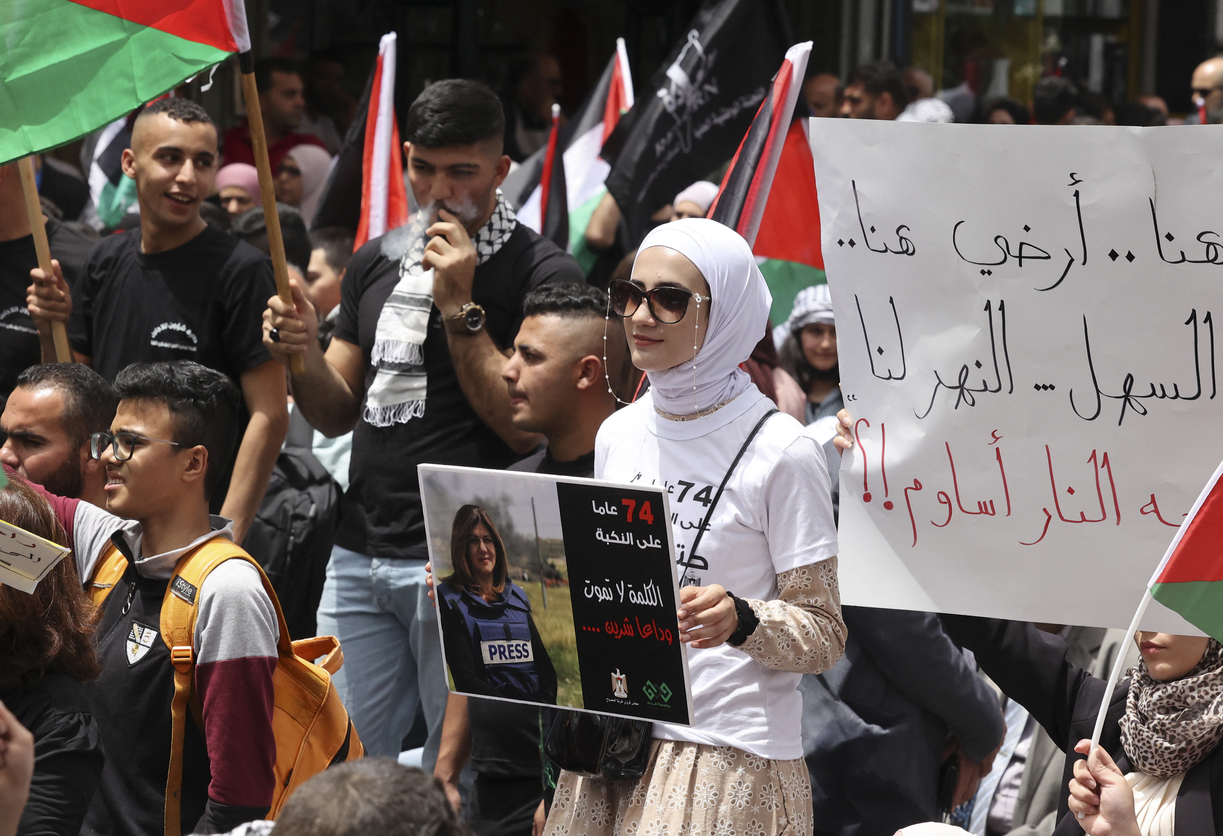 Palestinian wave national flags as they march in a rally marking the 74th anniversary of the "Nakba" or "catastrophe"