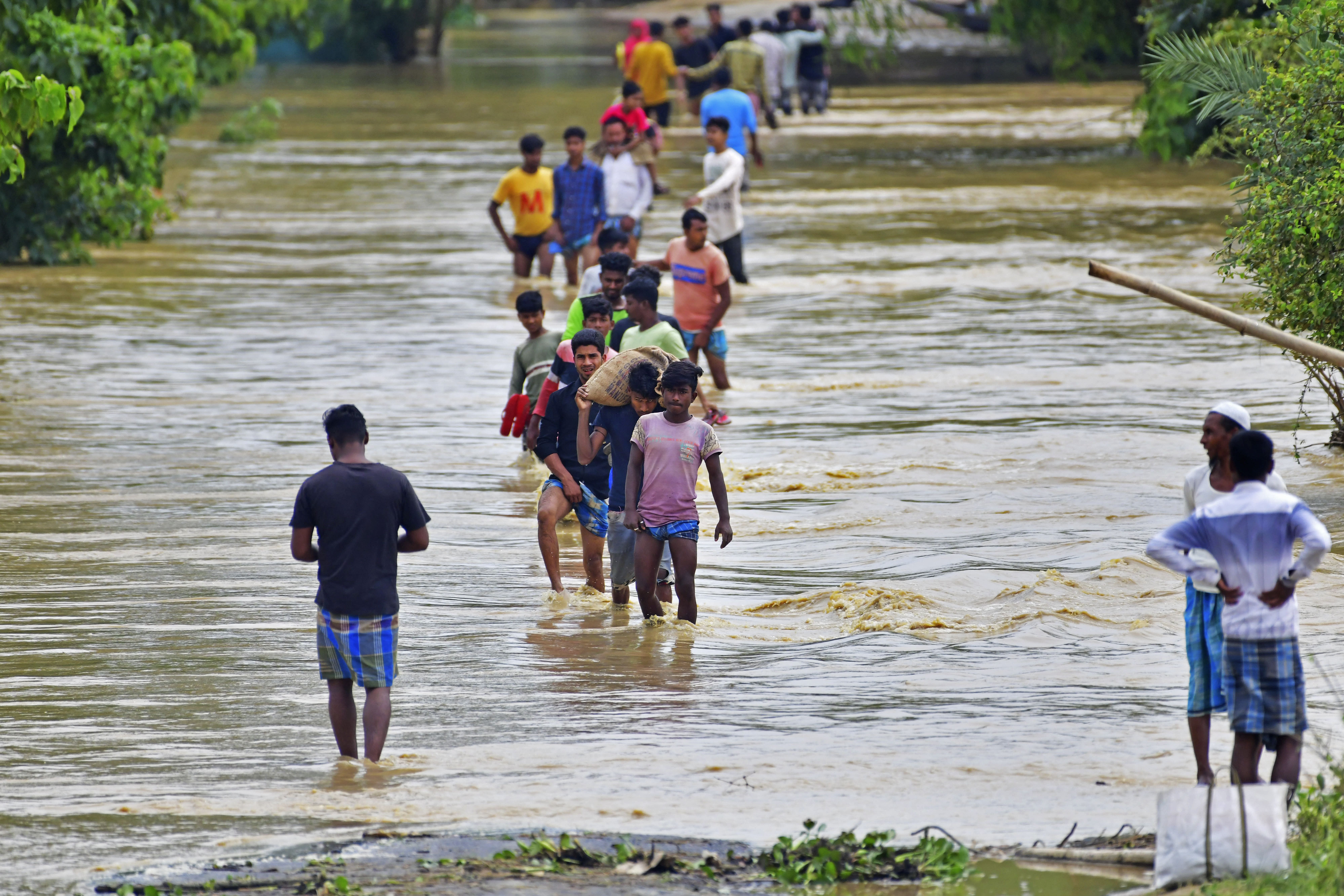 Villagers wade through a flooded road after heavy rains in Hojai district of India's Assam