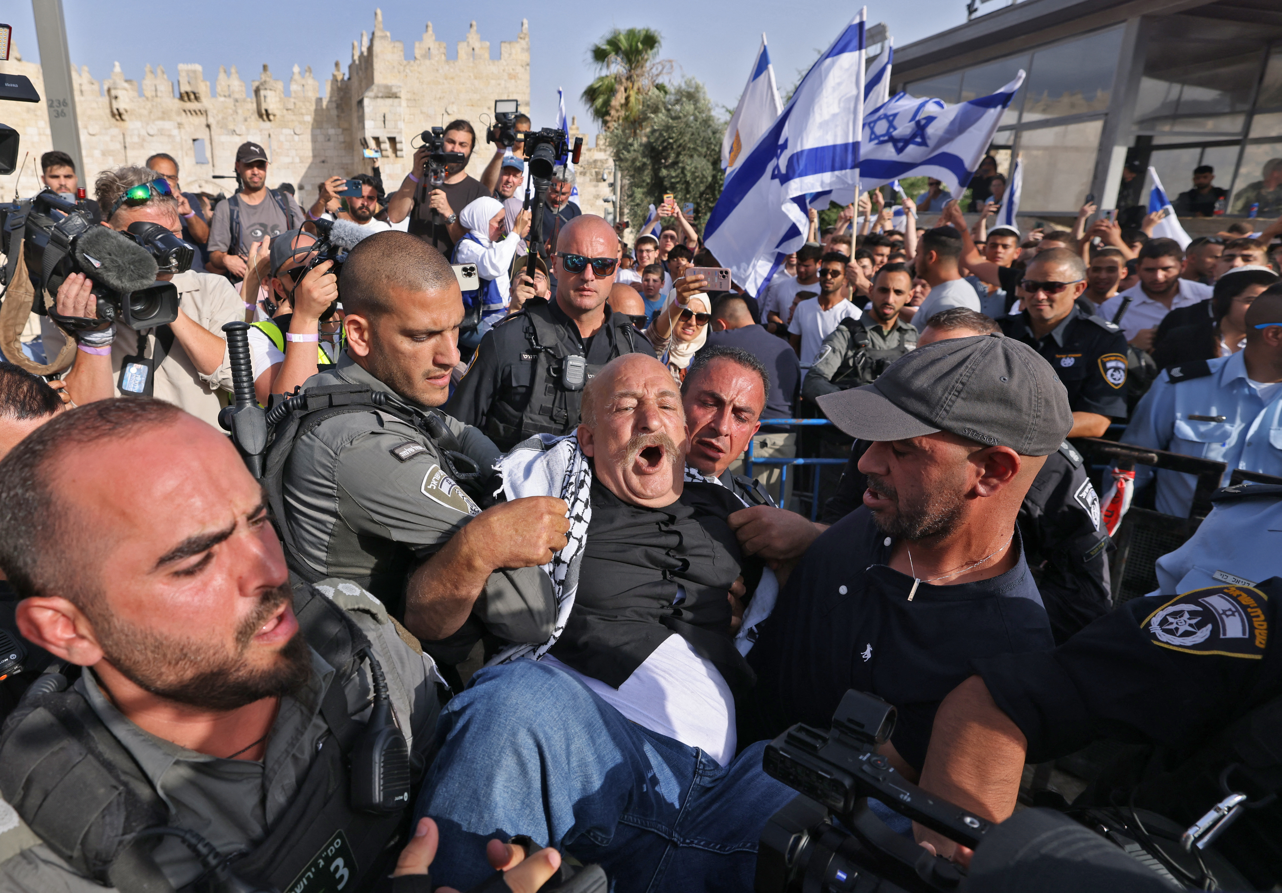 Israeli border guards carry a detained man wearing a Palestinian keffiyeh