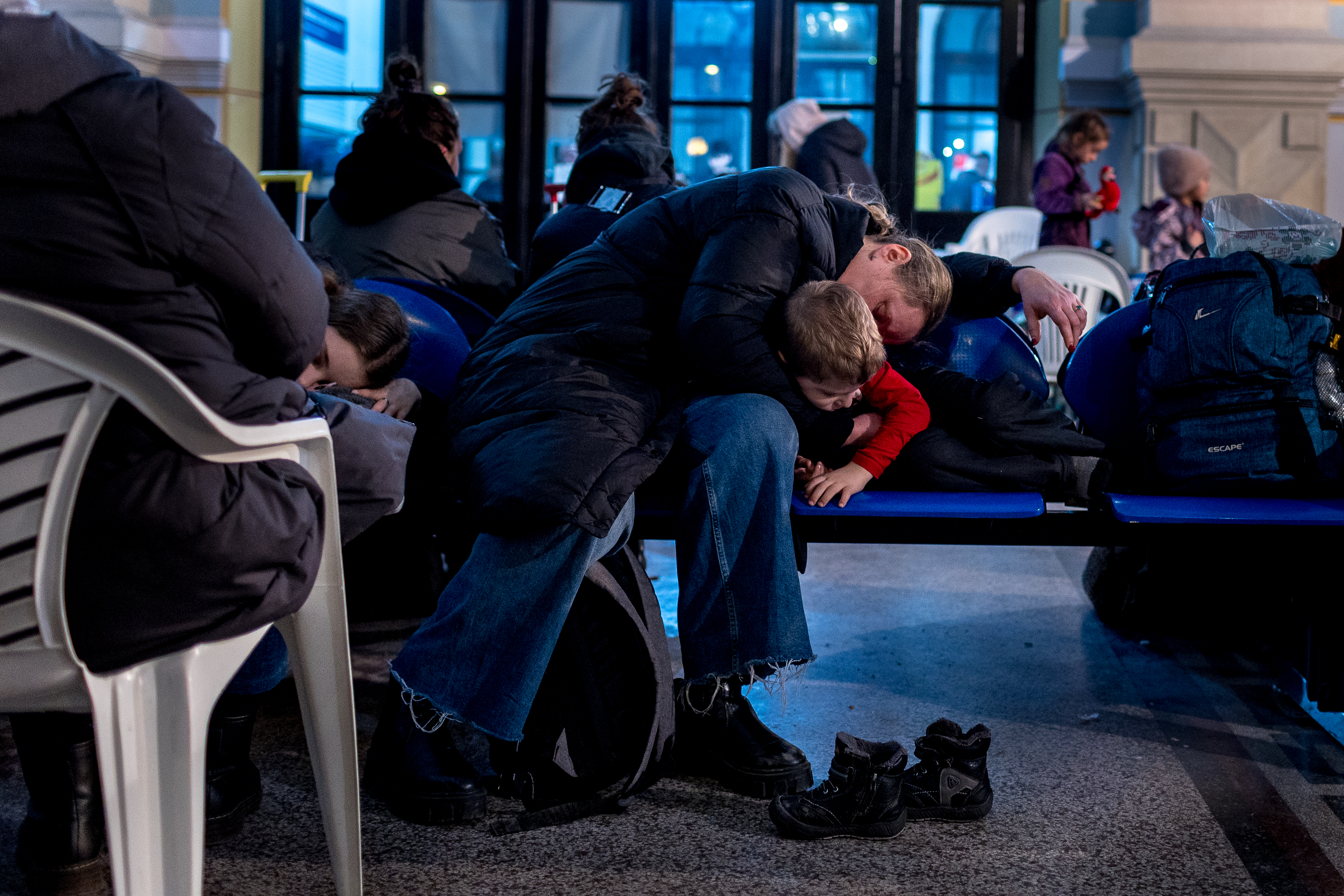 A woman and child sleep in a train station