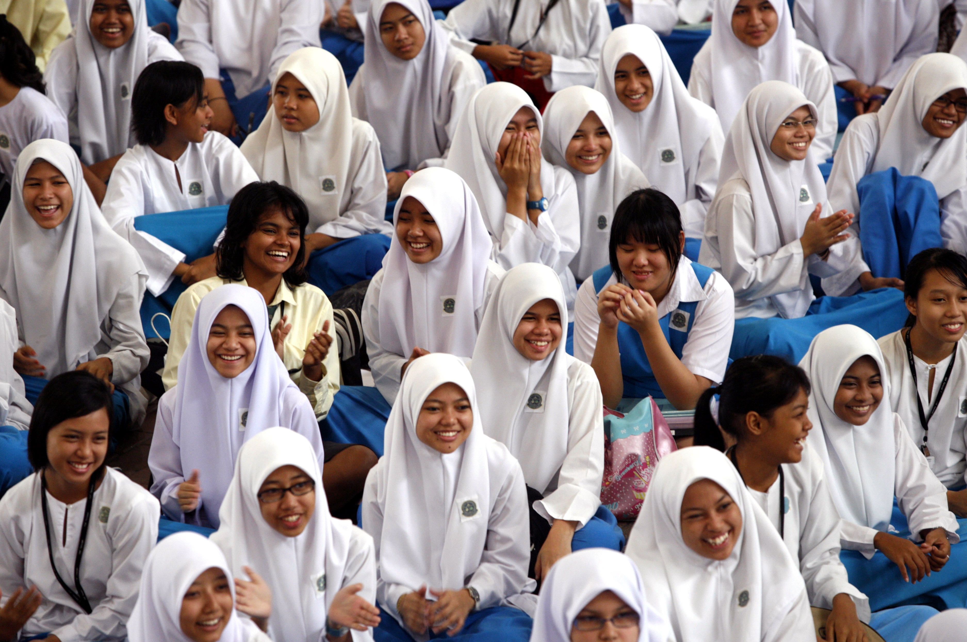 Young Malaysian girls including Muslim Malays, ethnic Indians and Chinese sit in a school hall in their uniforms