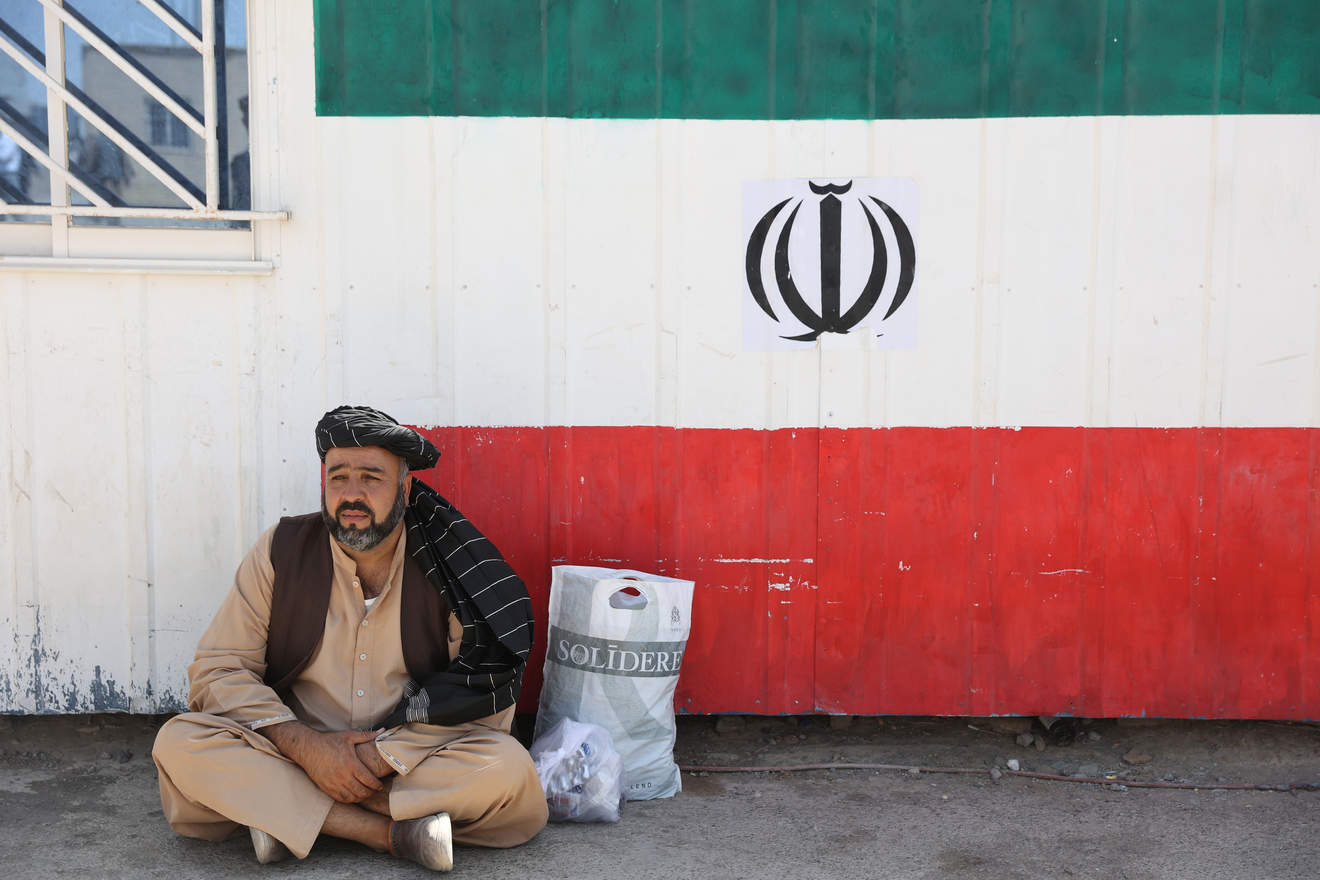 An Afghan man sits at the Dowqarun border crossing between Iran and Afghanistan, Razavi Khorasan Province, Iran