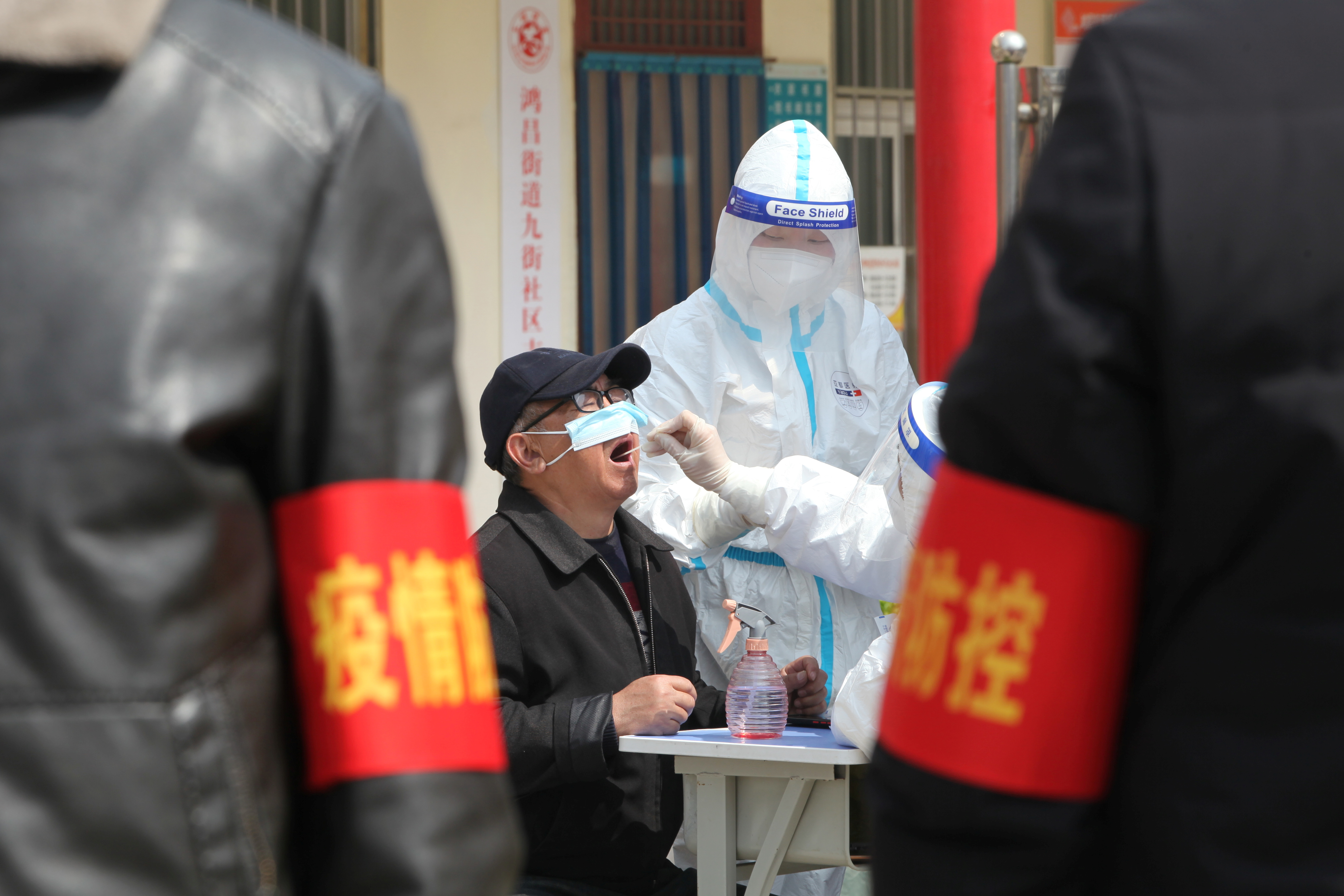 A medical worker in a protective suit collects a swab sample from a resident for nucleic acid testing during a mass testing for the coronavirus disease