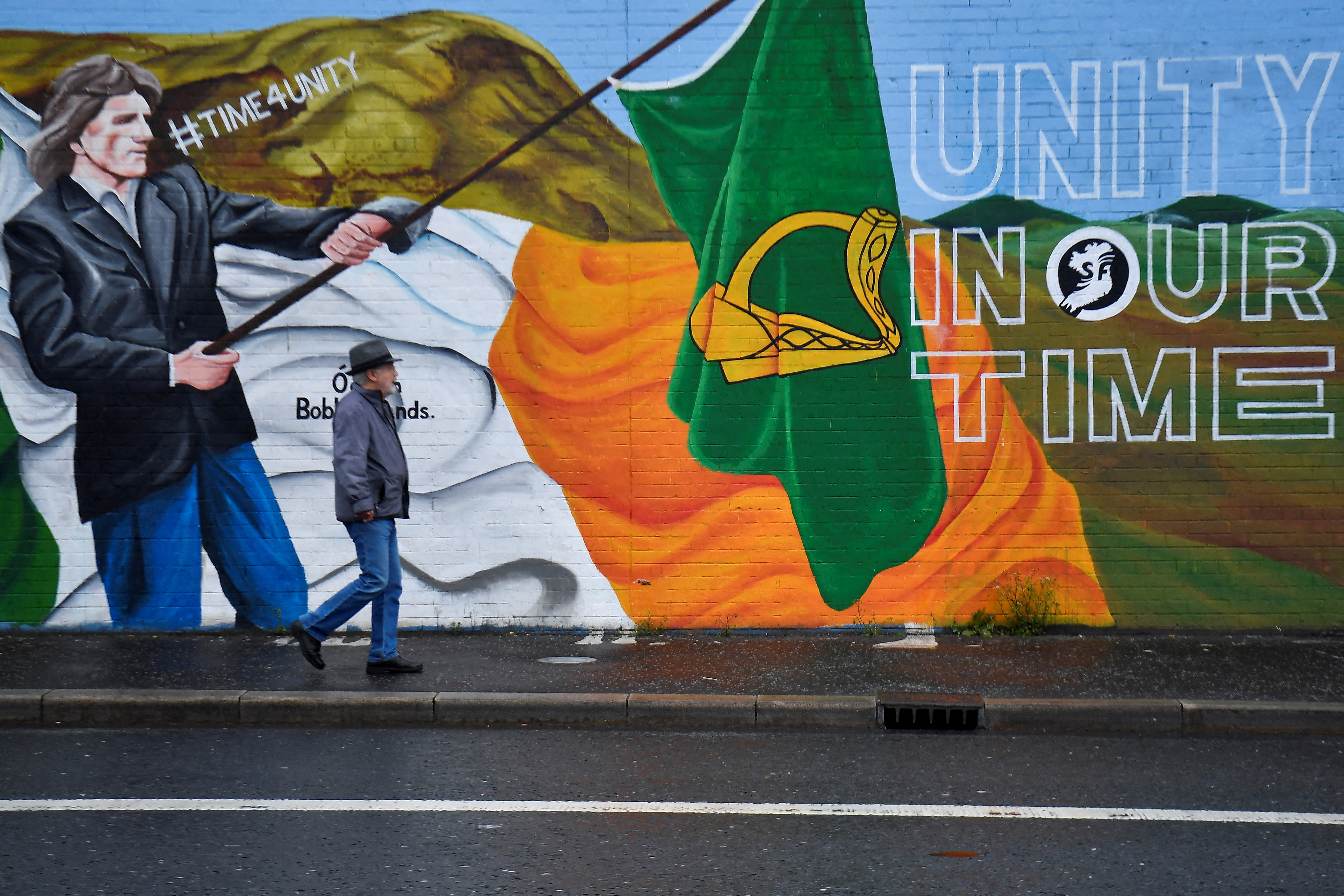 A man walks past a mural saying "Unity in our Time"