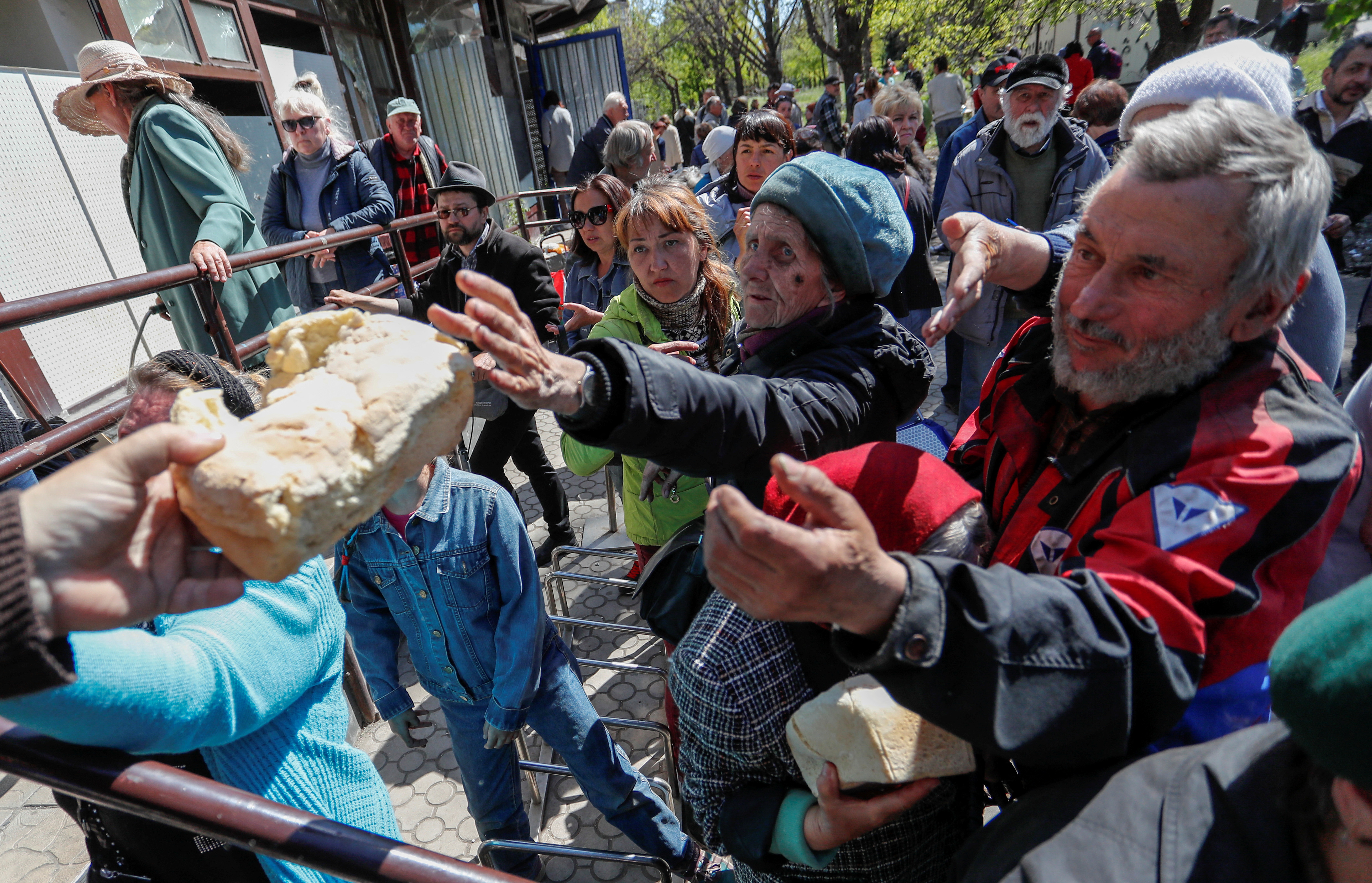 People receive bread during the distribution of humanitarian aid in the course of Ukraine-Russia conflict in the southern port city of Mariupol, Ukraine