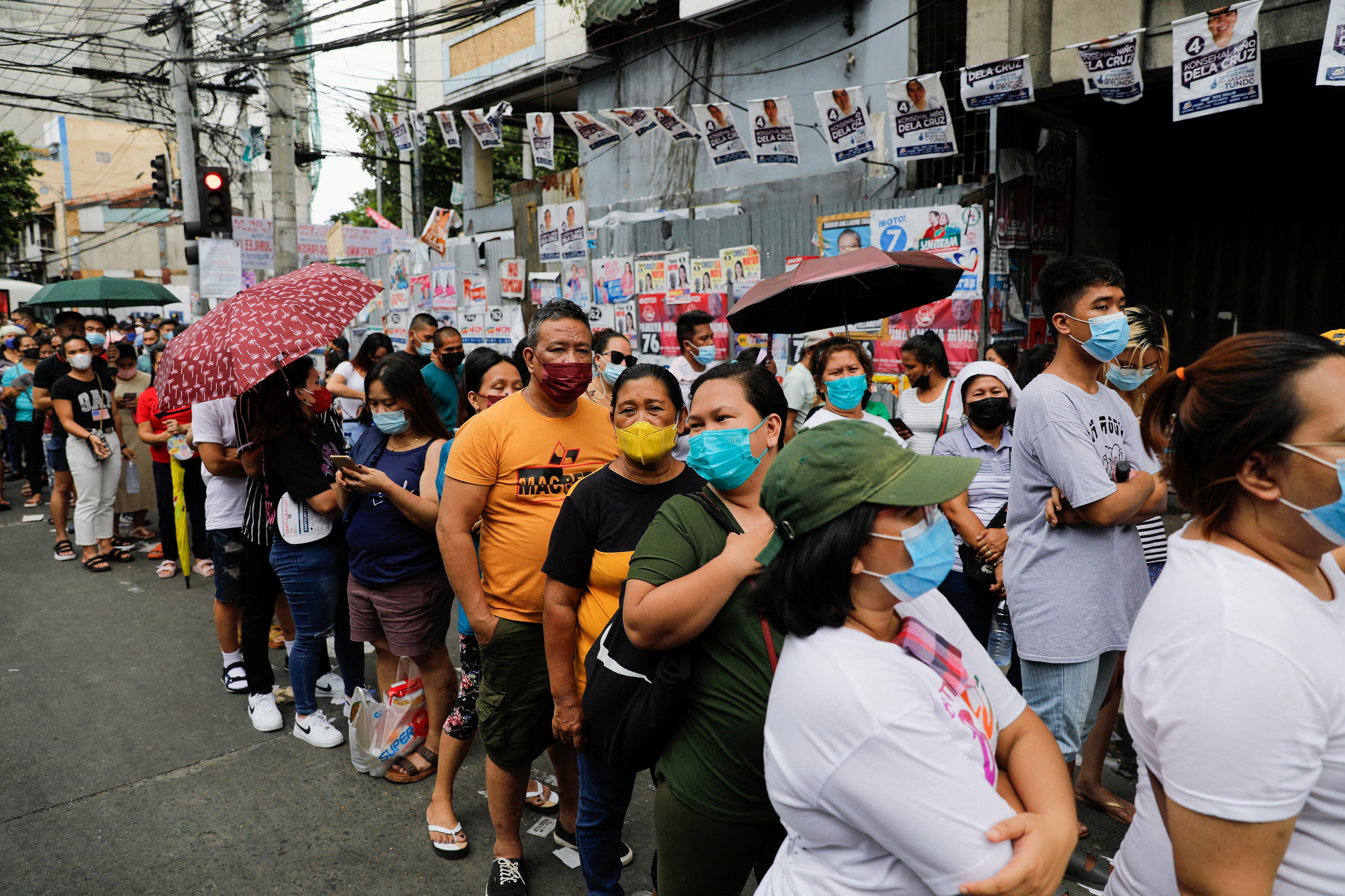 People queue outside a polling precinct to cast their ballots, during the national elections in Tondo, Metro Manila, Philippines