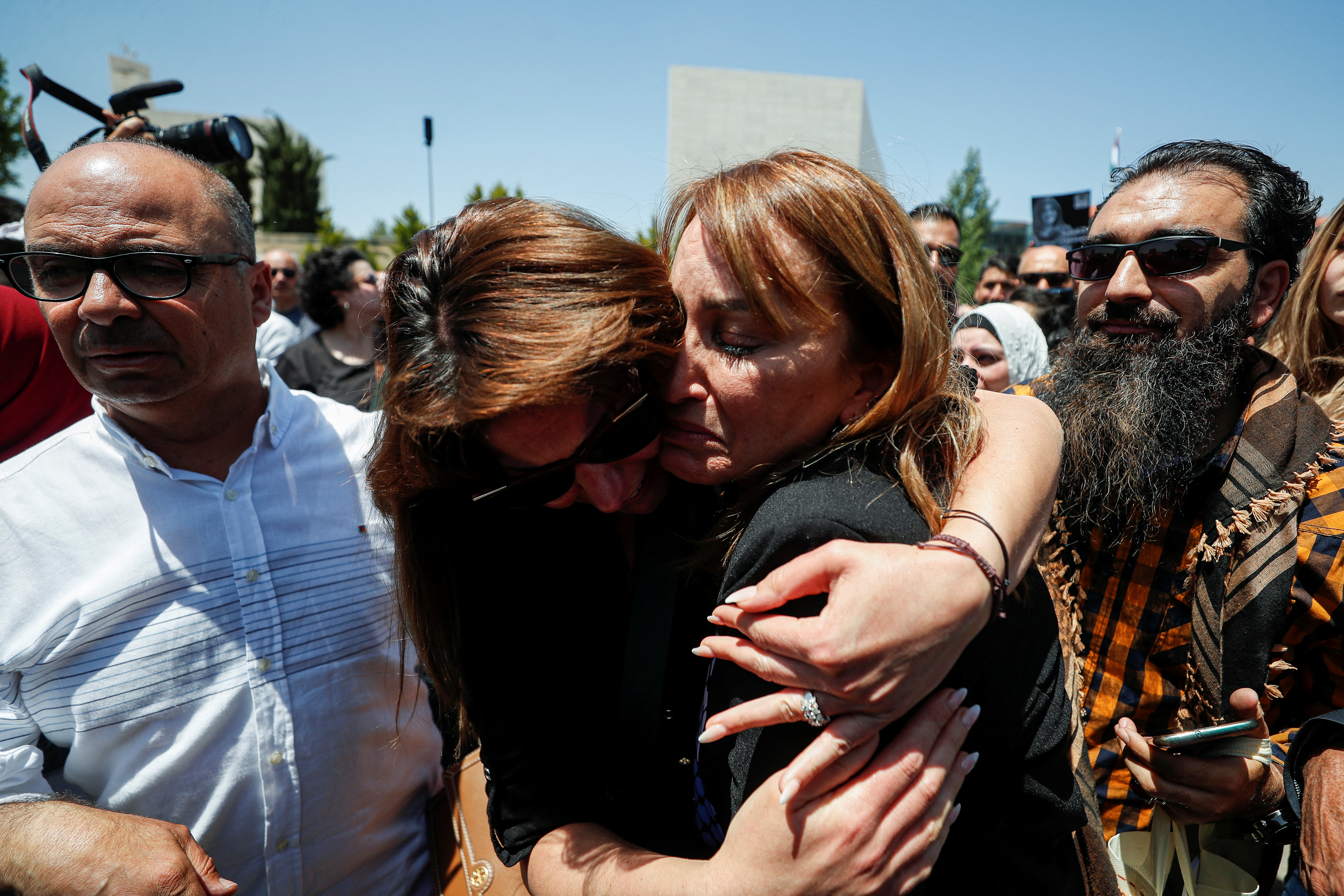 Colleagues embrace each other as they bit the farewell to Al Jazeera journalist Shireen Abu Akleh