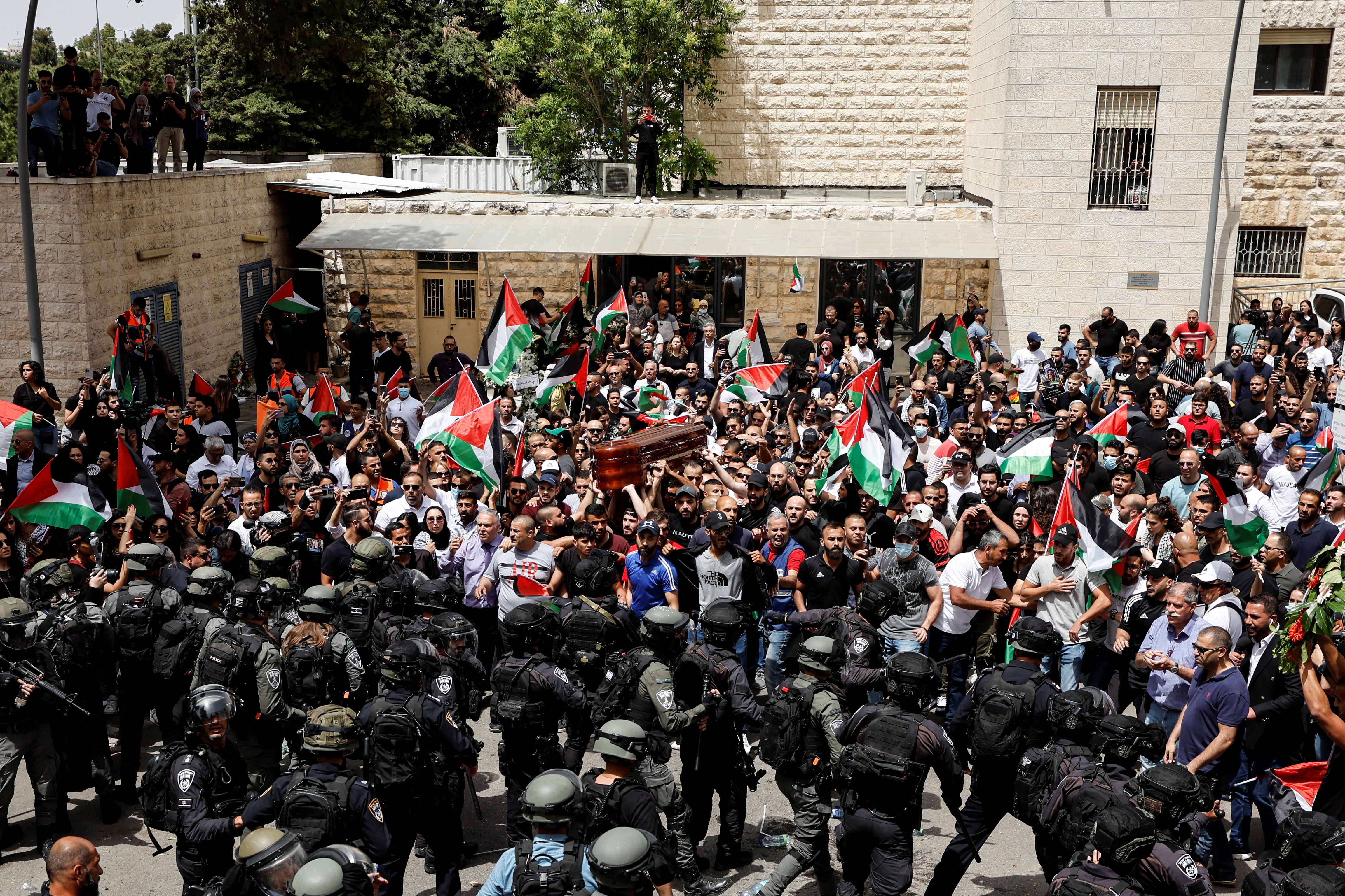 Family and friends carry the coffin of Al Jazeera reporter Shireen Abu Akleh, who was killed during an Israeli raid in Jenin in the occupied West Bank, as Israeli security forces stand guard, during her funeral in Jerusalem, May 13, 2022. REUTERS/Ammar Awad
