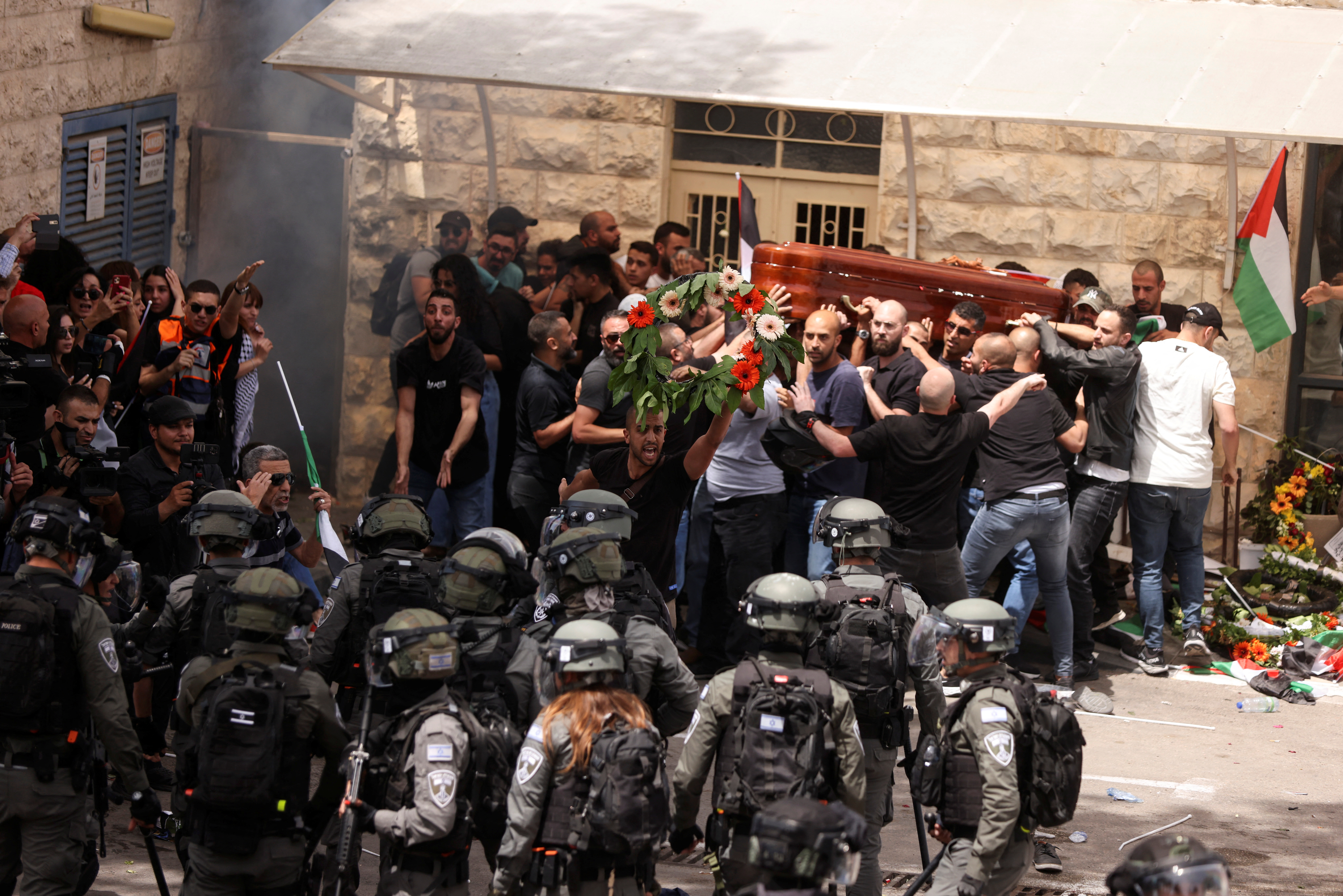 Family and friends carry the coffin of Al Jazeera reporter Shireen Abu Akleh, who was killed during an Israeli raid in Jenin in the occupied West Bank, next to Israeli security forces, during her funeral in Jerusalem, May 13, 2022. REUTERS/Ammar Awad