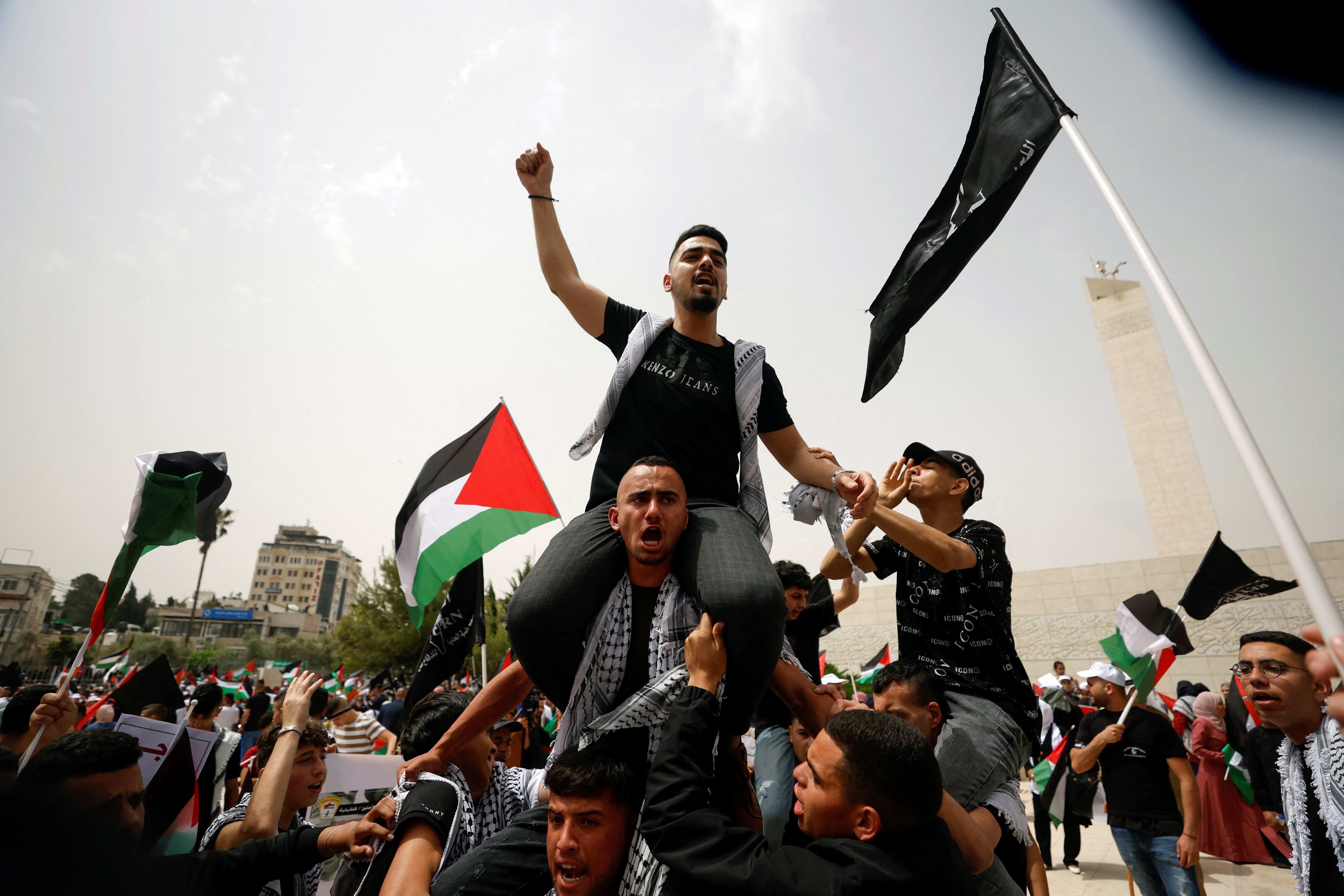 Palestinian wave national flags as they march in a rally marking the 74th anniversary of the "Nakba" or "catastrophe"
