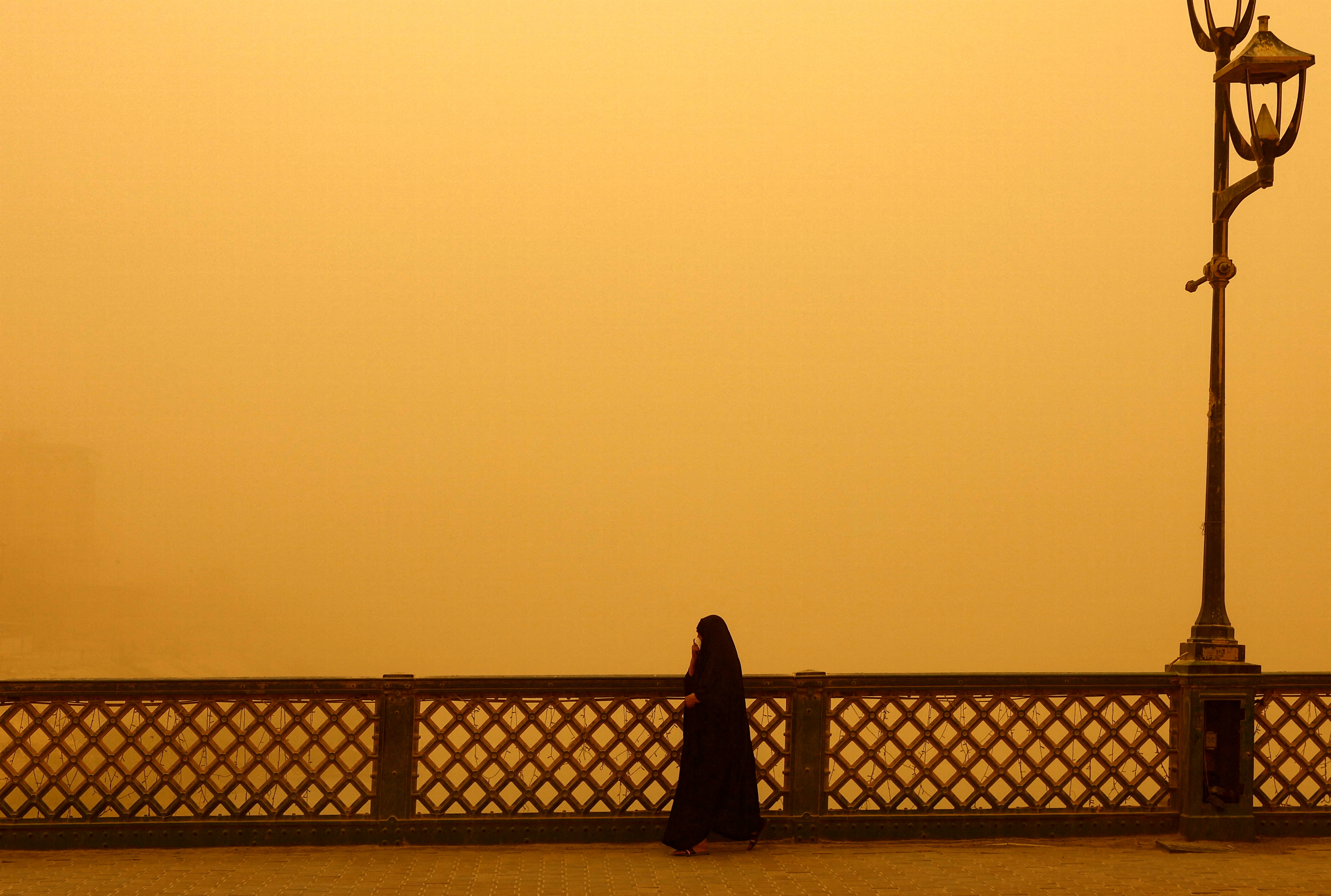 A woman walks on a bridge during a sandstorm in Baghdad, Iraq