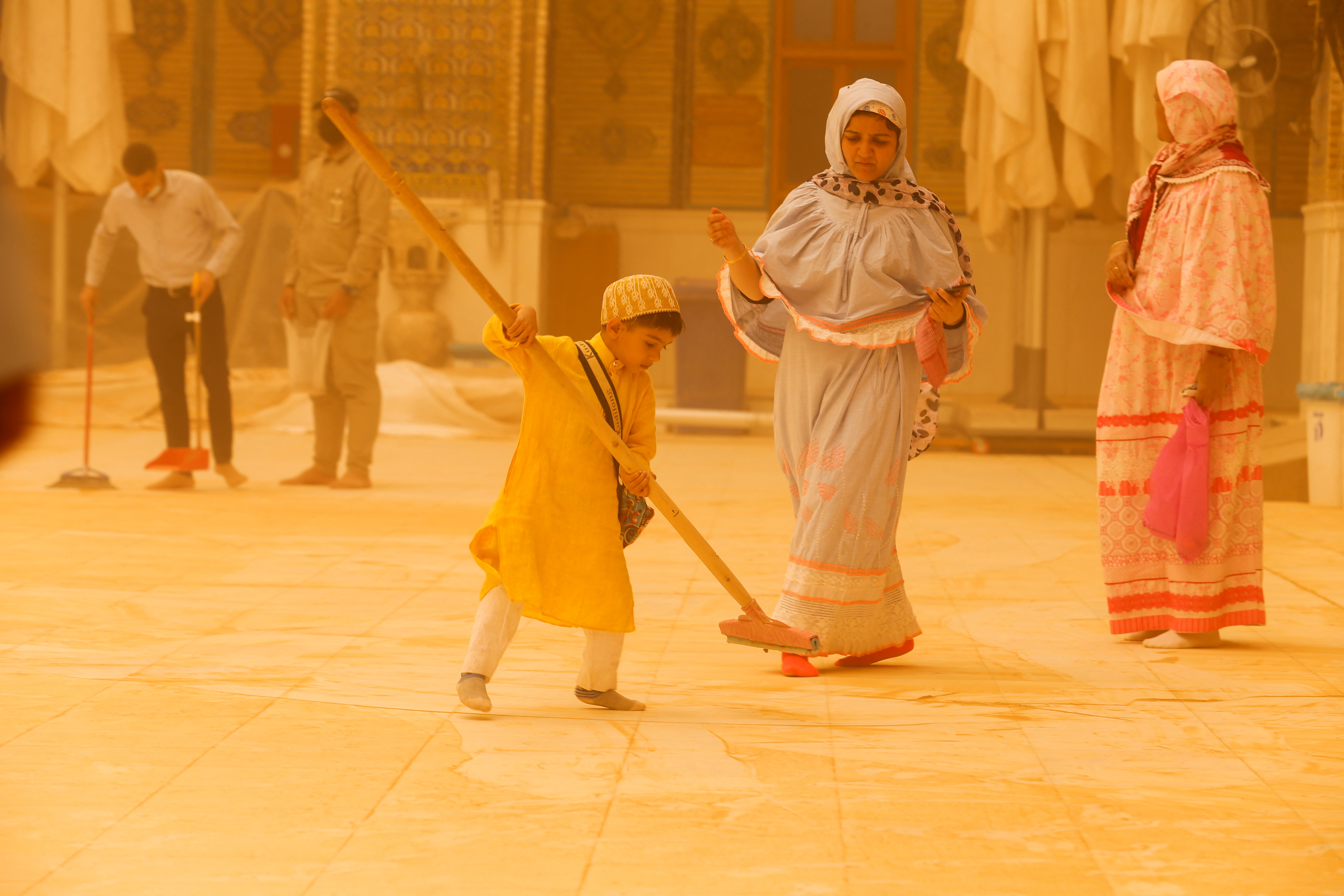 A child sweeps the floor during a sandstorm at the Imam Ali Shrine in Najaf, Iraq