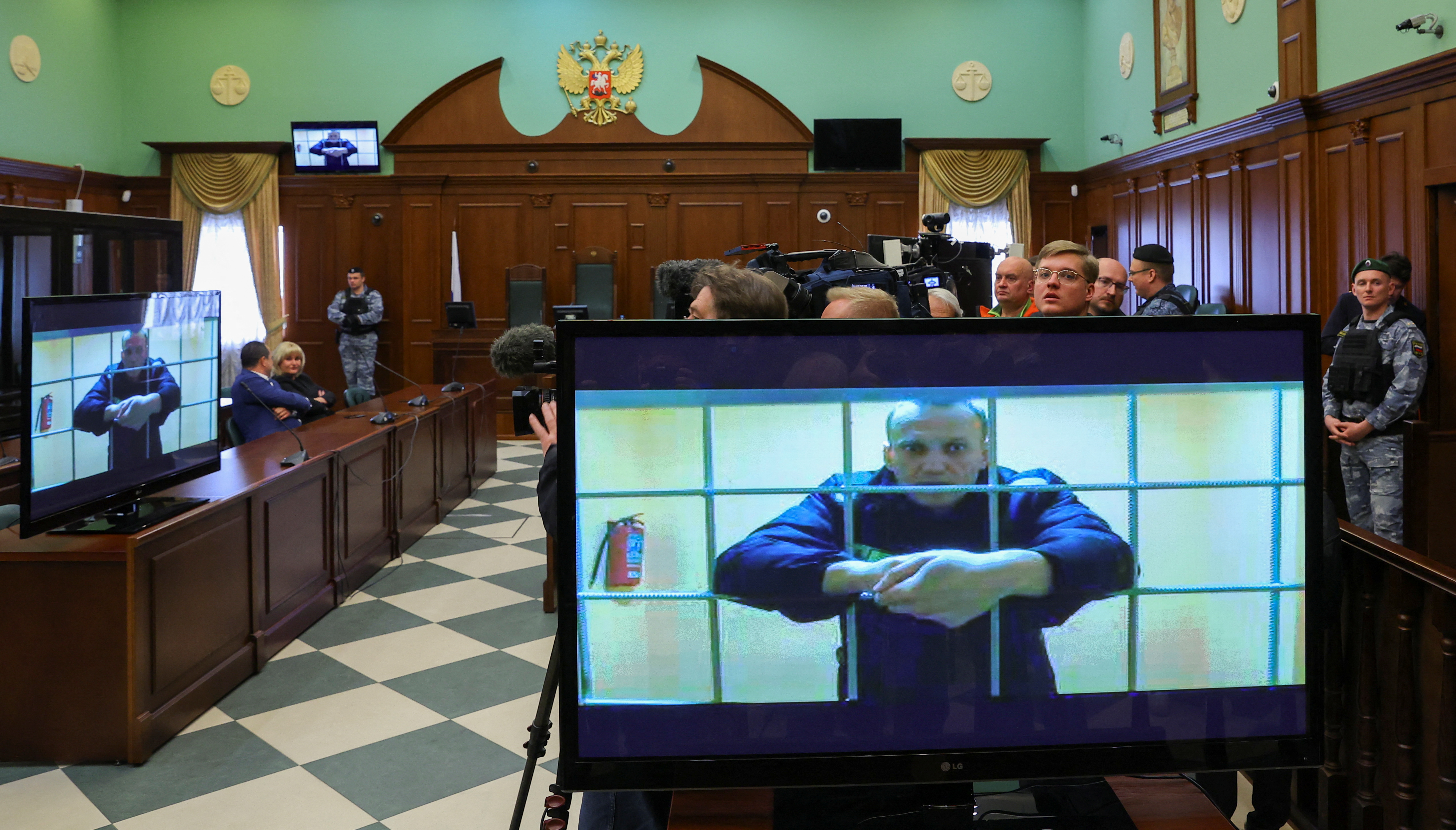 Russian opposition leader Alexey Navalny is seen on screens via a video link from the IK-2 corrective penal colony in Pokrov during a court hearing