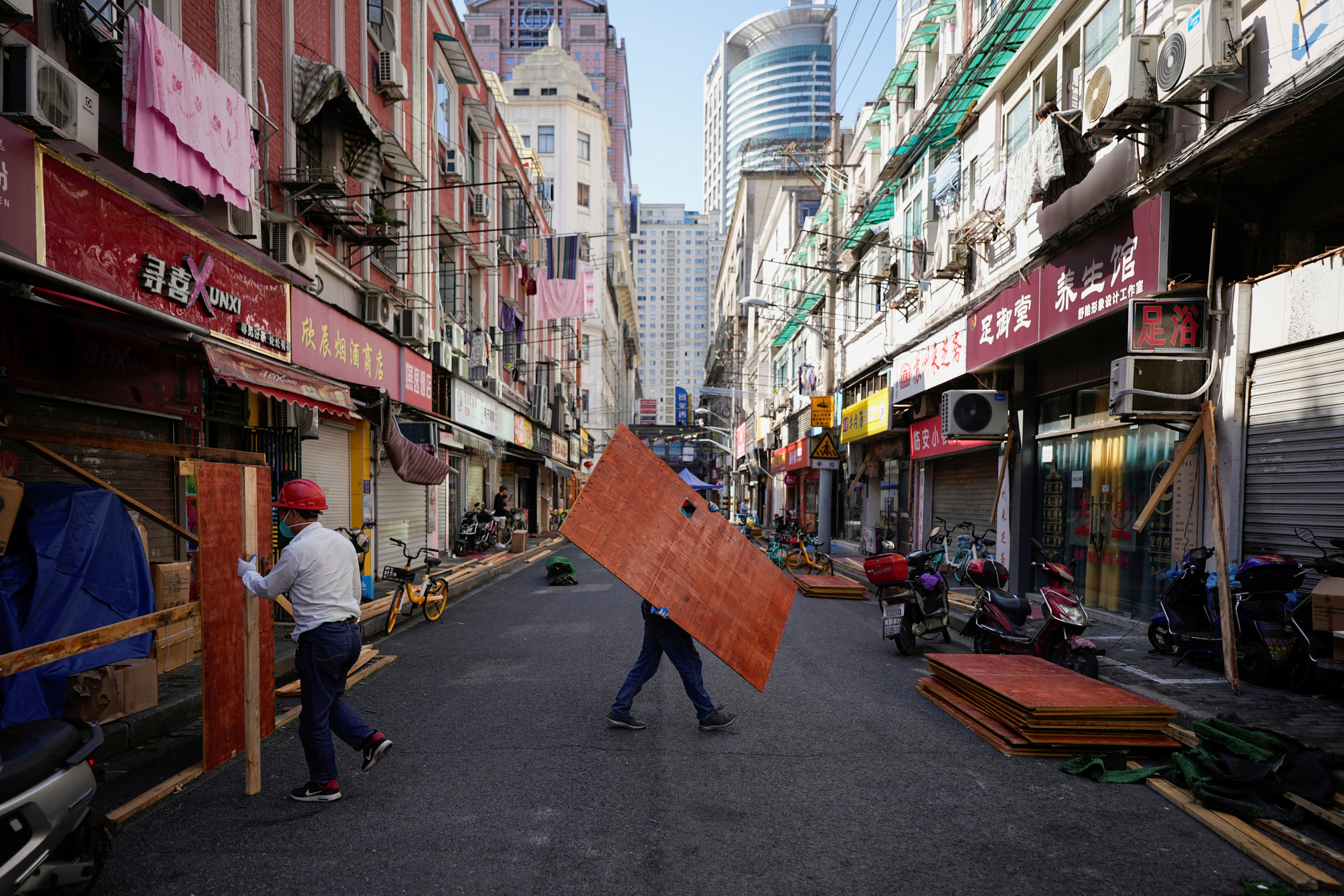 Workers dismantle a barrier along a Shanghai street as the city prepares to end its COVID lockdown
