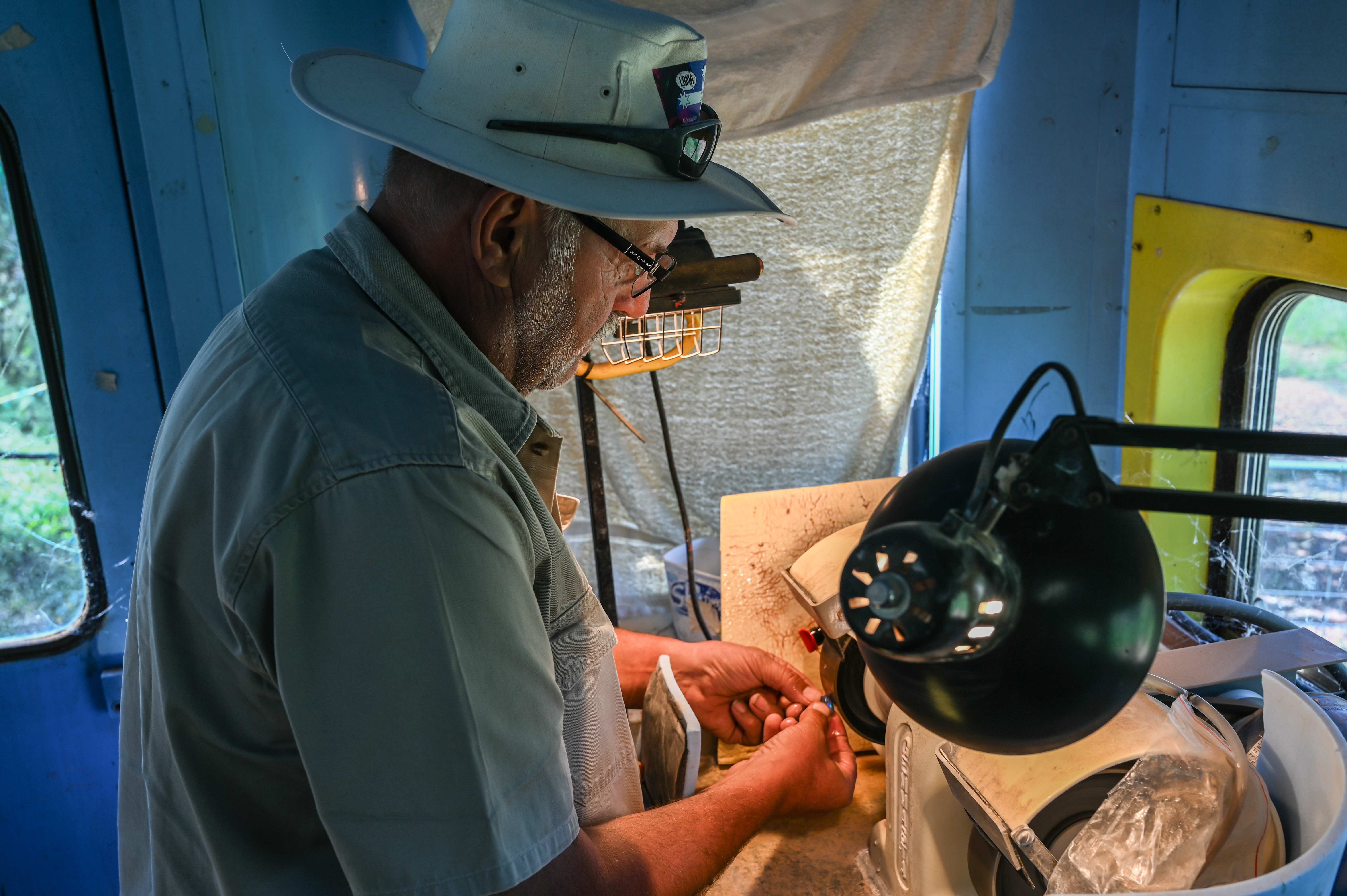 A photo of Sebastian demonstrating how to cut and polish and opal.
