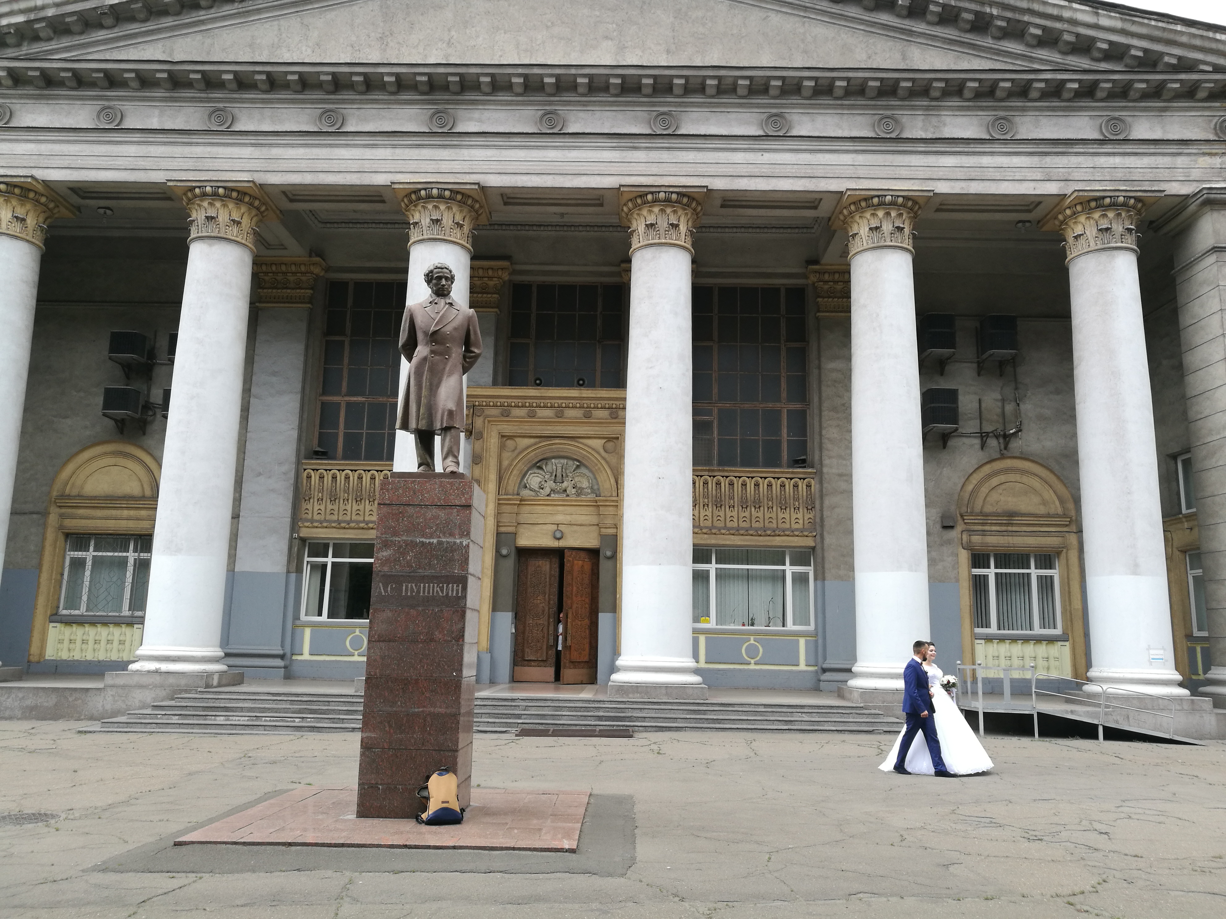 Newly married couple walking in front of Pushkin statue in Kyiv