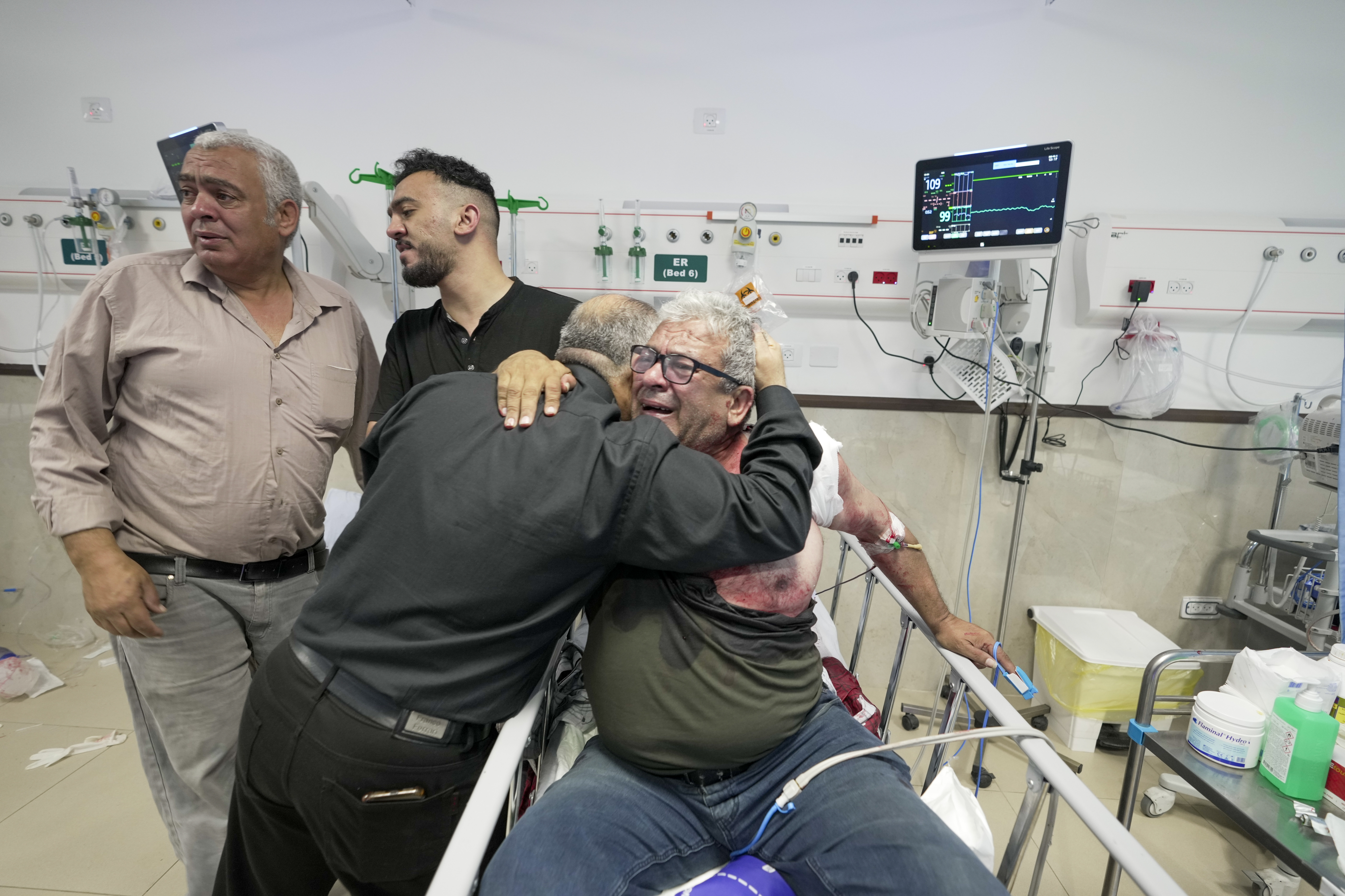 An injured journalist is being hugged by one of the colleagues of killed journalist Shireen Abu Akleh