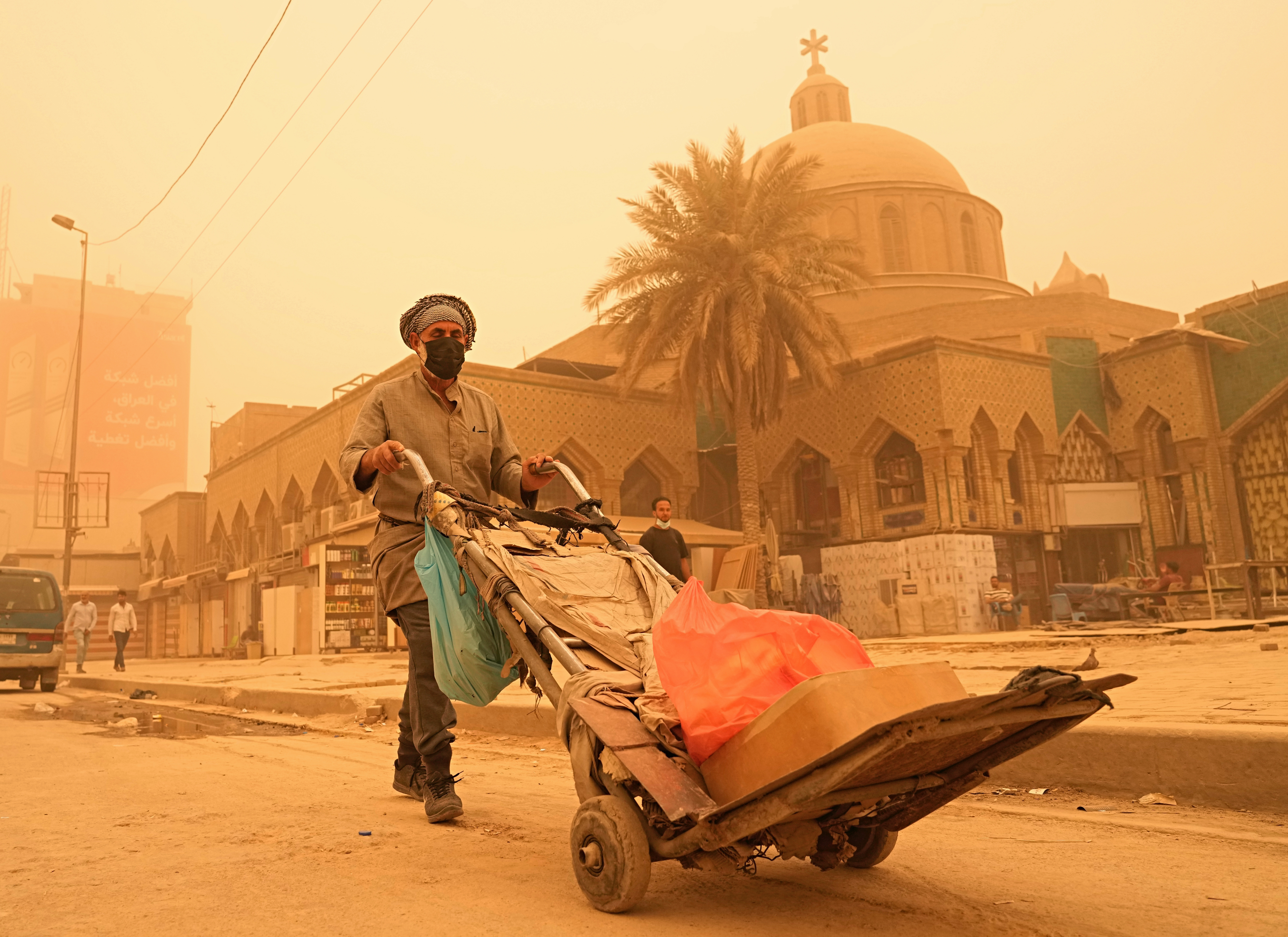 A man pushes a cart during a sandstorm in Baghdad, Iraq