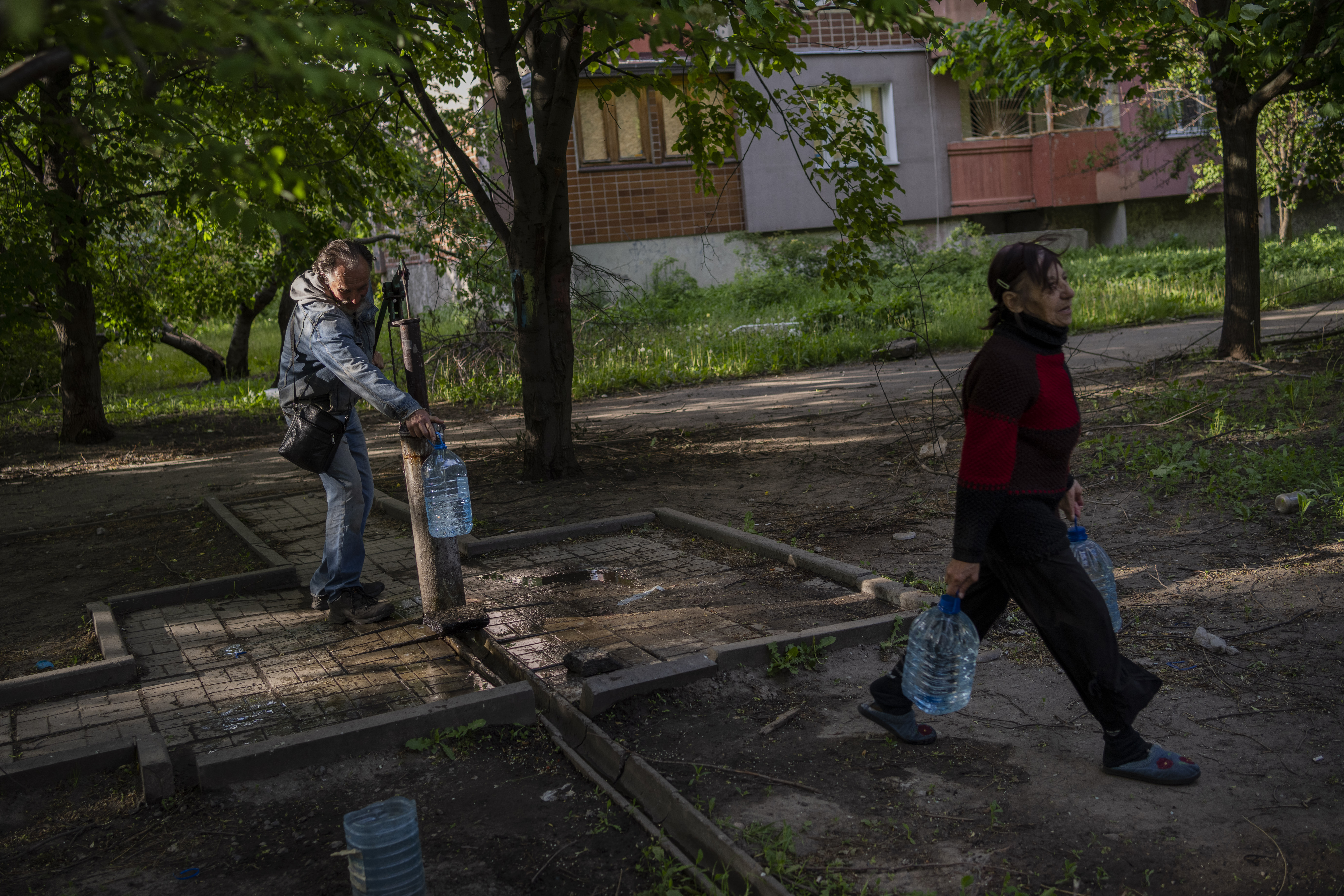 Residents of a shelled neighbourhood collect water from a public water pump in Kharkiv, eastern Ukraine, Thursday, May 19, 2022.