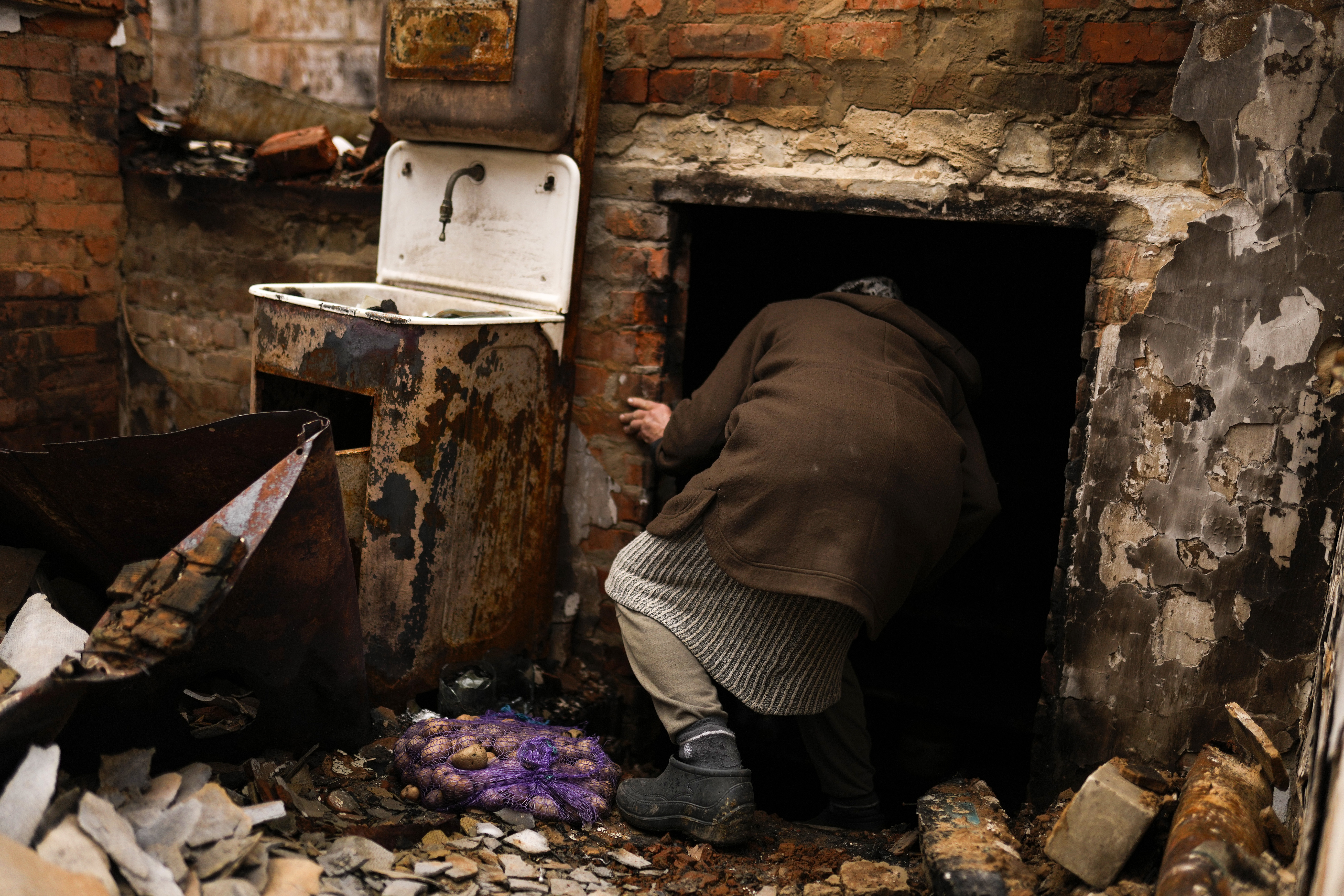 Olena Koptyl, 63, enters the basement of her destroyed home in the aftermath of a battle between Russian and Ukrainian troops on the outskirts of Chernihiv in northern Ukraine, Saturday, April 23, 2022