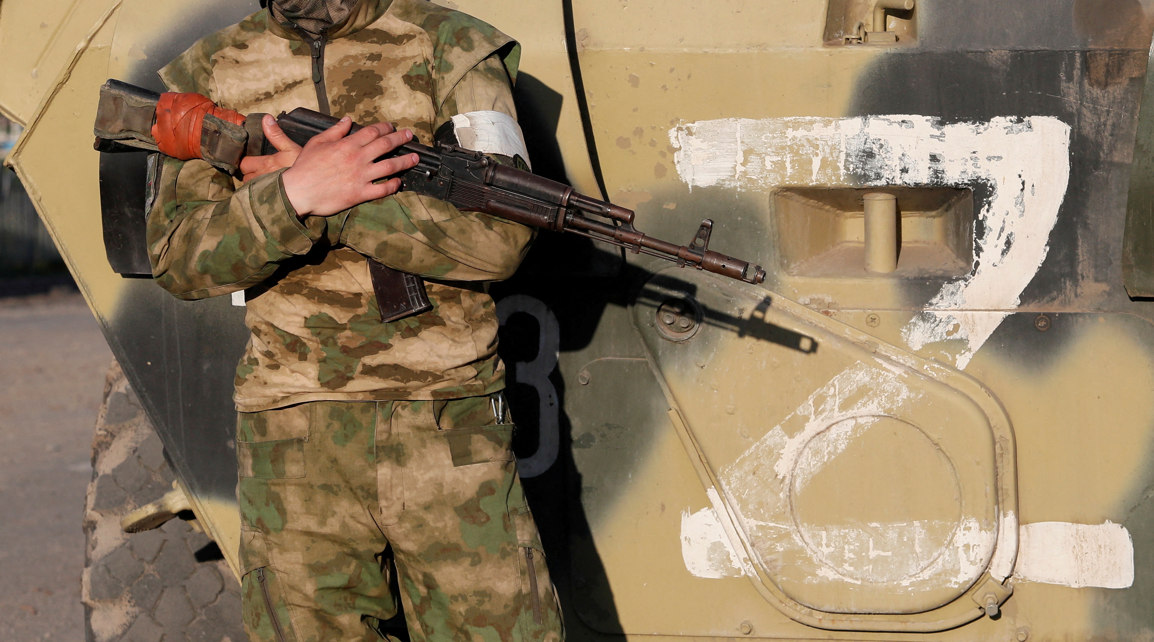 A service member of pro-Russian troops stands guard next to a combat vehicle, with the symbol "Z" seen on its side, before the expected evacuation of wounded Ukrainian soldiers from the besieged Azovstal steel mill