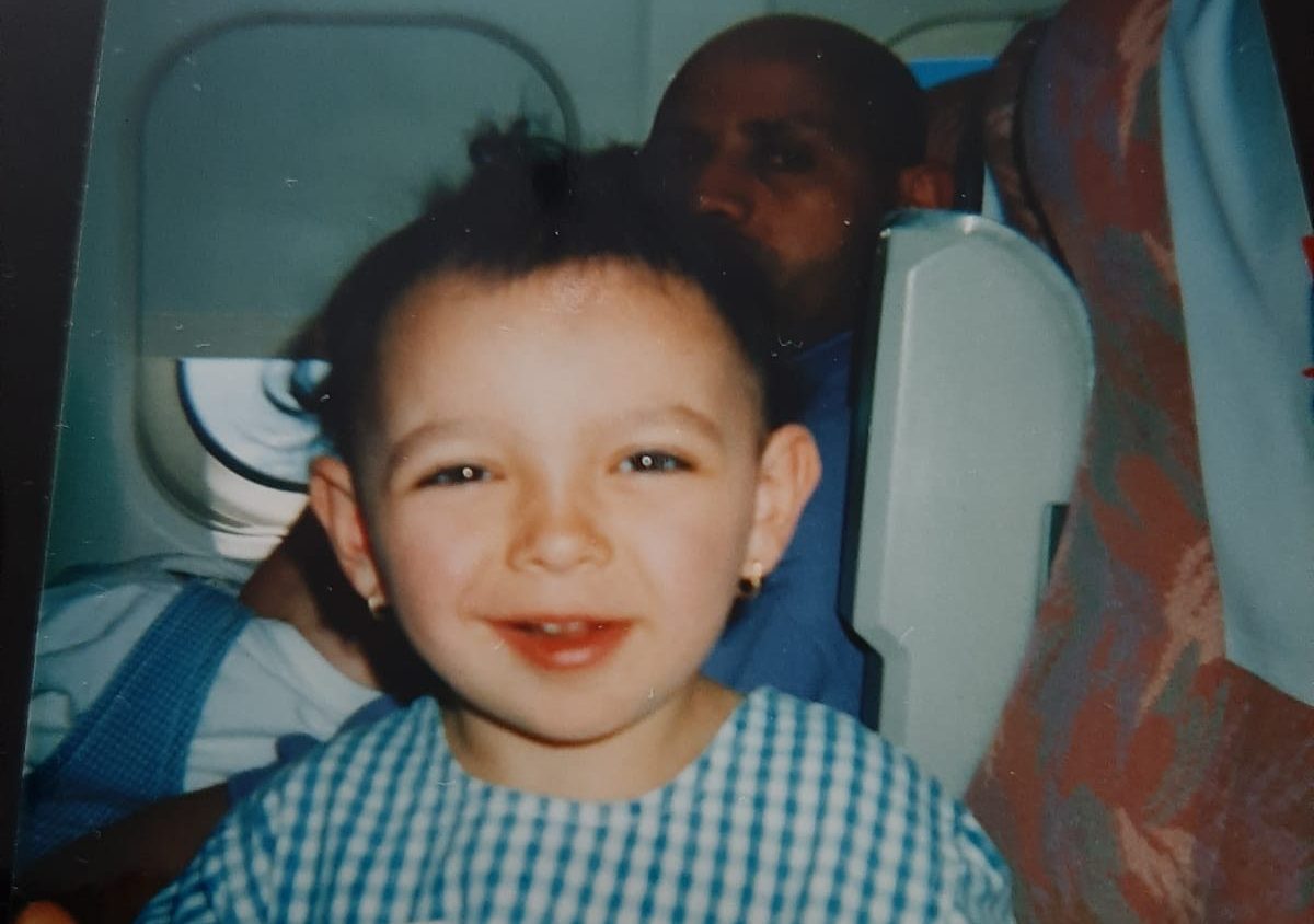 Photo of the author as a small chlid on a flight to Libya, with her father looking on from behind her
