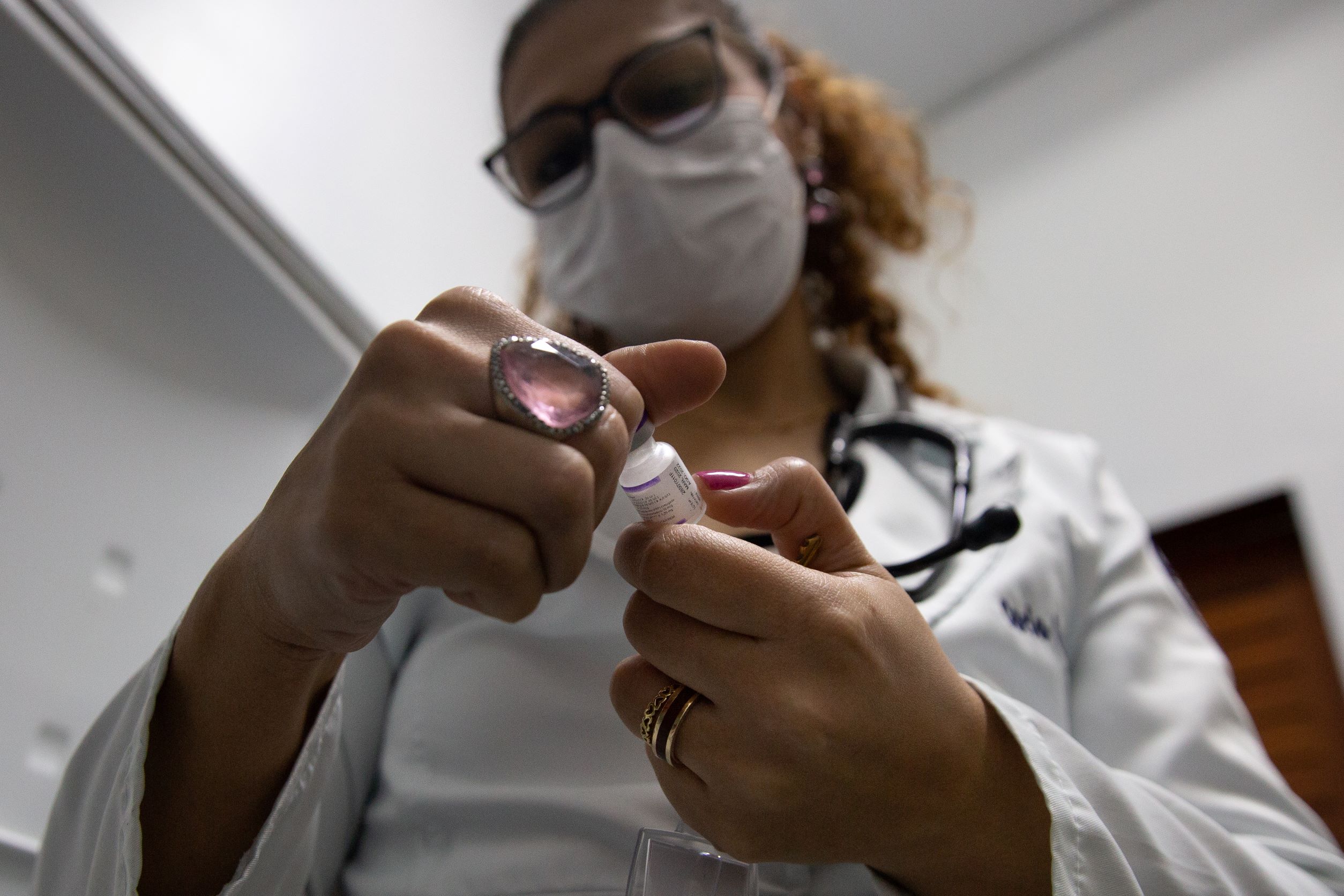 Pediatrician Carla Carvalho reads the side of a vial of measles vaccine