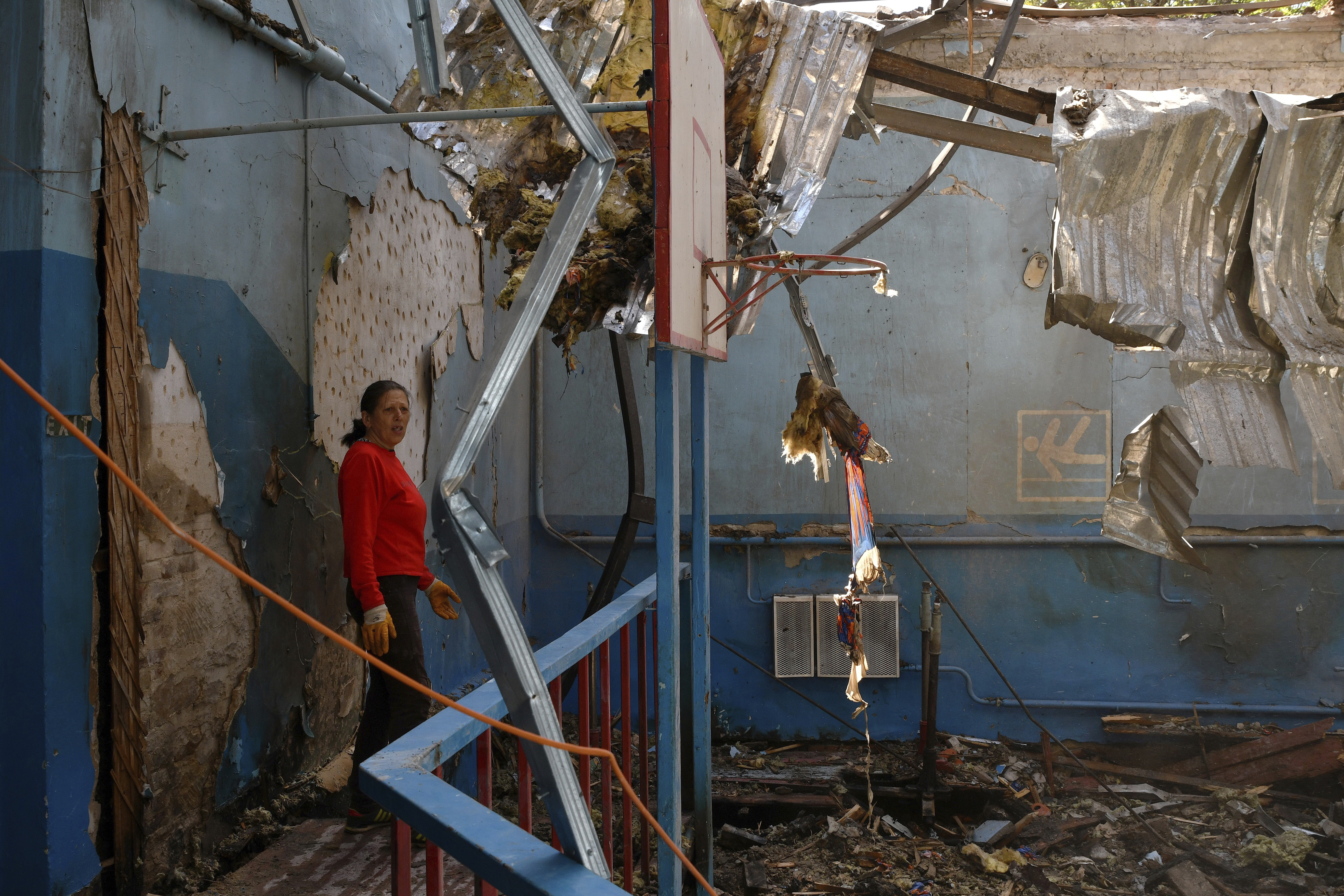 A sports teacher stands in a destroyed gymnasium of a school after Russian shelling in the village of Druzhkivka.