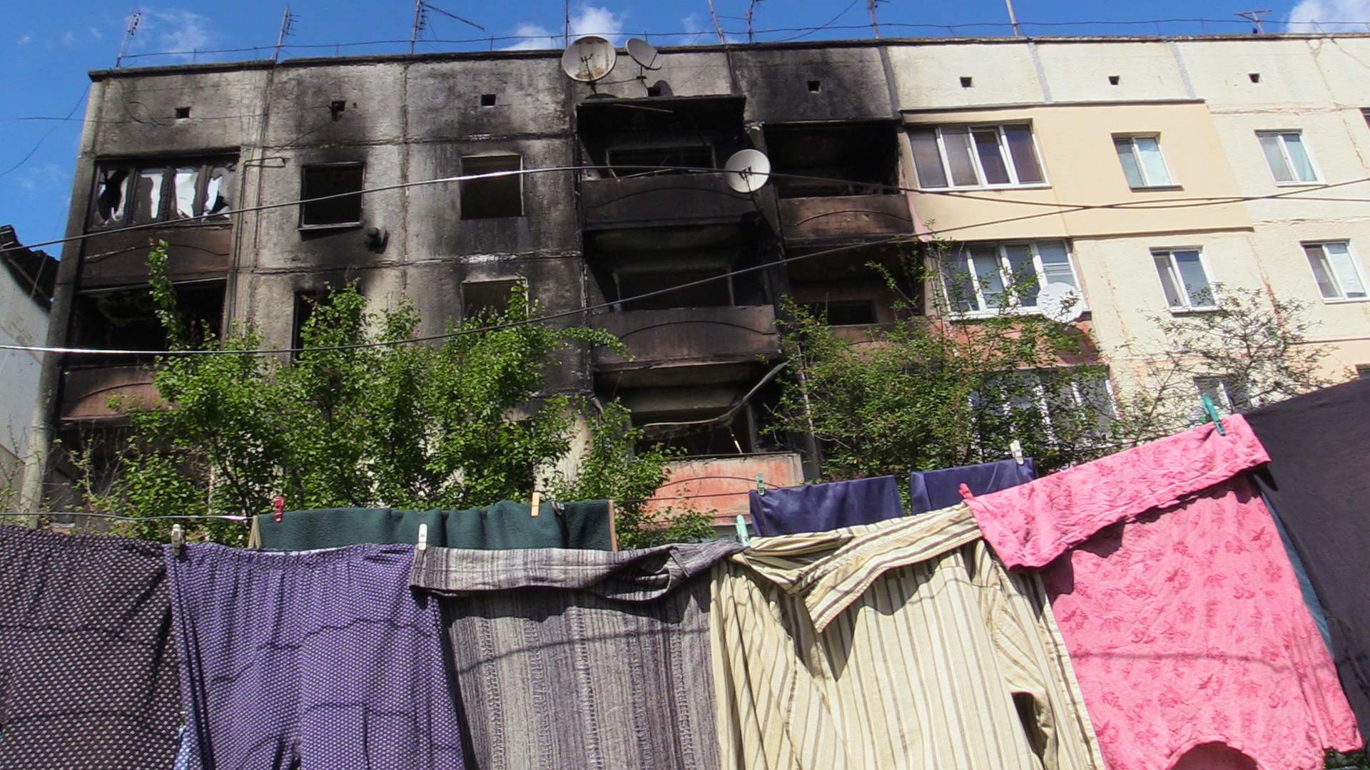 Drying laundry near a shelling-damaged apartment building in Makariv,