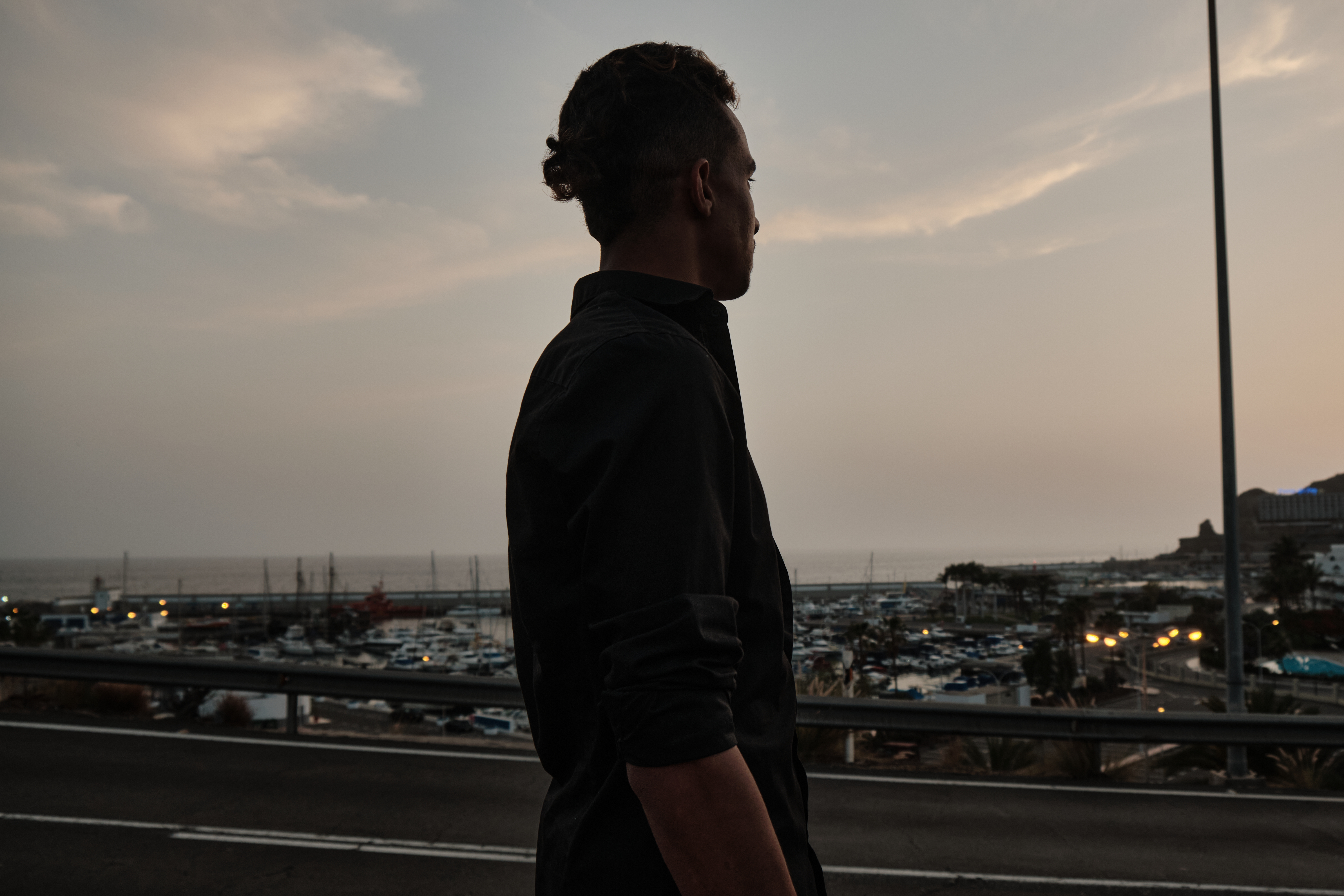 A photo of Youssef, 23, from Morocco, overlooks the little harbour of Puerto Rico, in Gran Canaria.