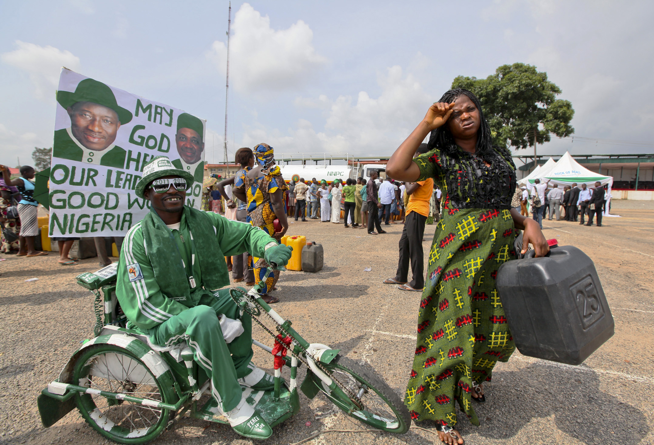 A disabled man rides outside a fuel station where people queue to buy kerosene, in Nigeria's capital Abuja