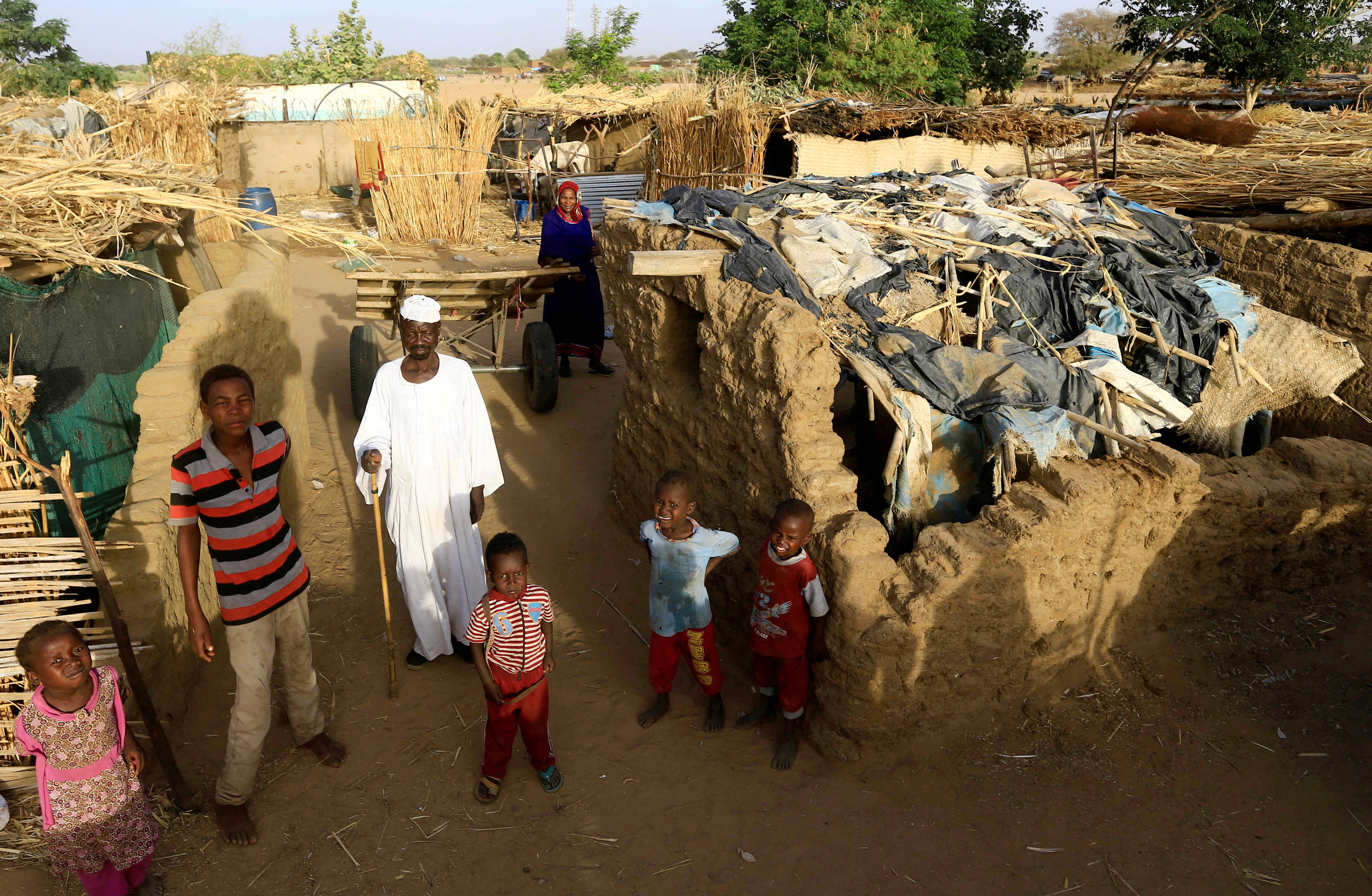 An internally displaced Sudanese family poses for a photograph outside their makeshift shelter within the Kalma camp for internally displaced people in Darfur, Sudan