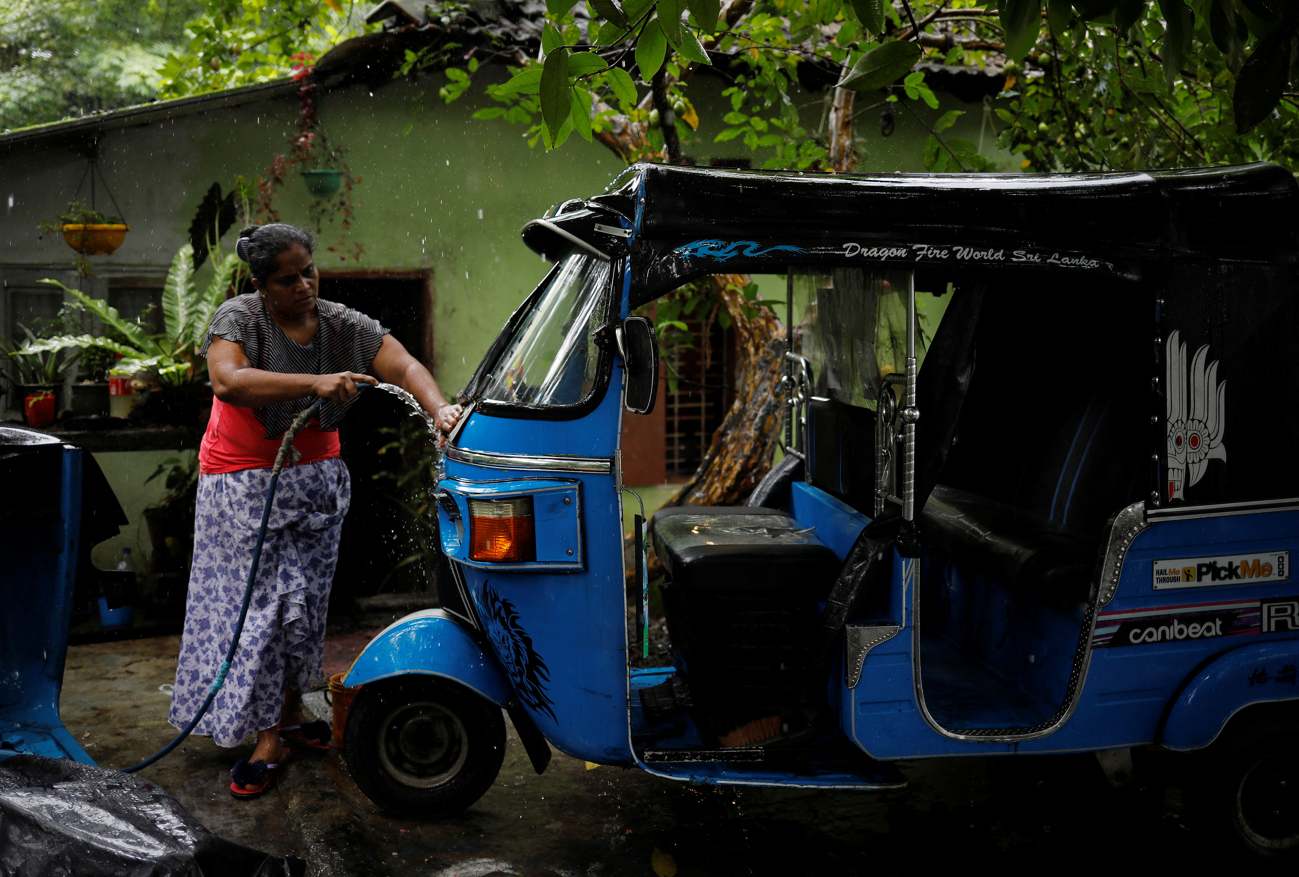 Lasanda Deepthi, 43, an auto-rickshaw driver for local ride hailing app PickMe, cleans her auto-rickshaw in Gonapola town, on the outskirts of Colombo, Sri Lanka