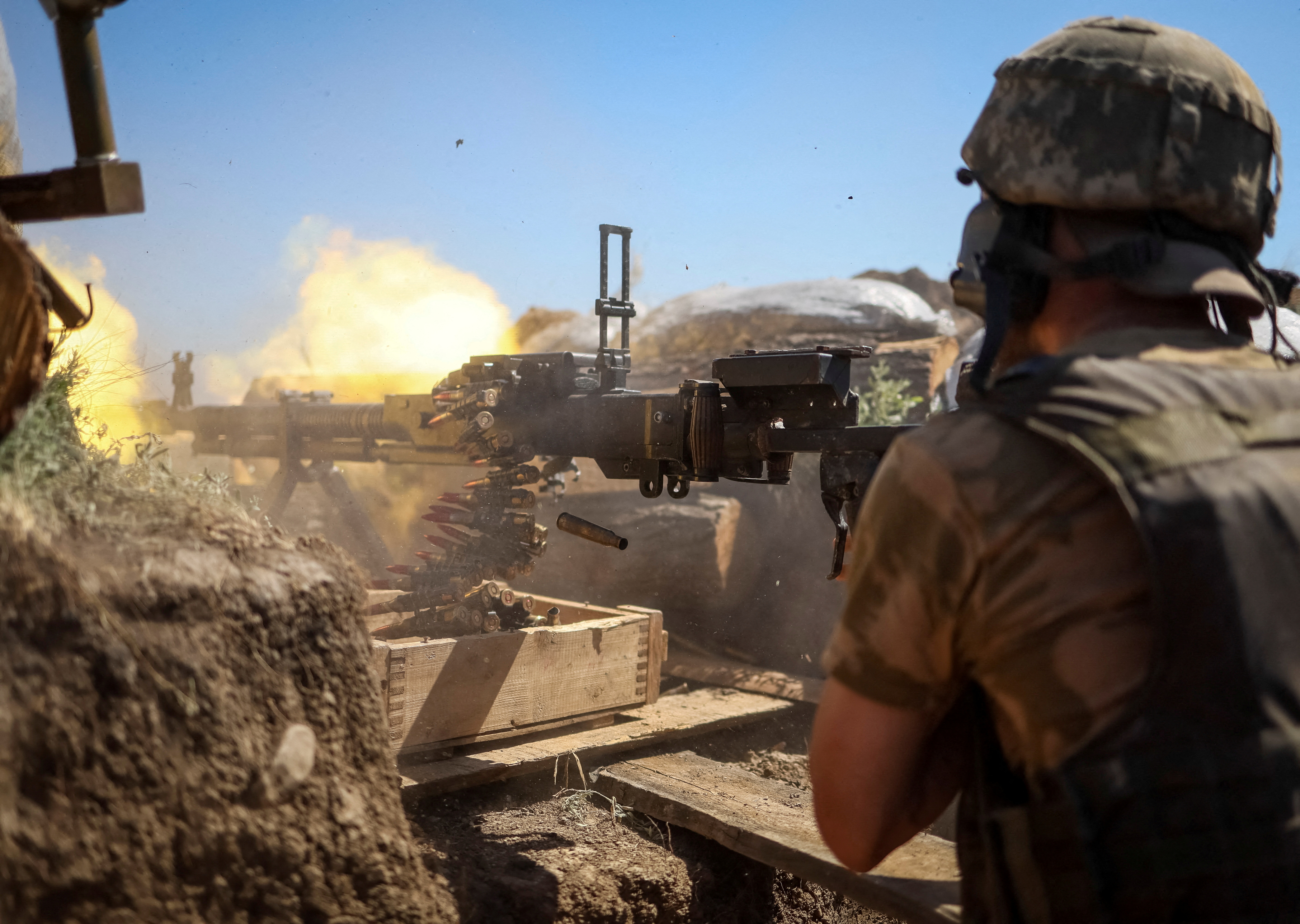 A Ukrainian service member shoots from a machine gun at a position on the front line in Donetsk region
