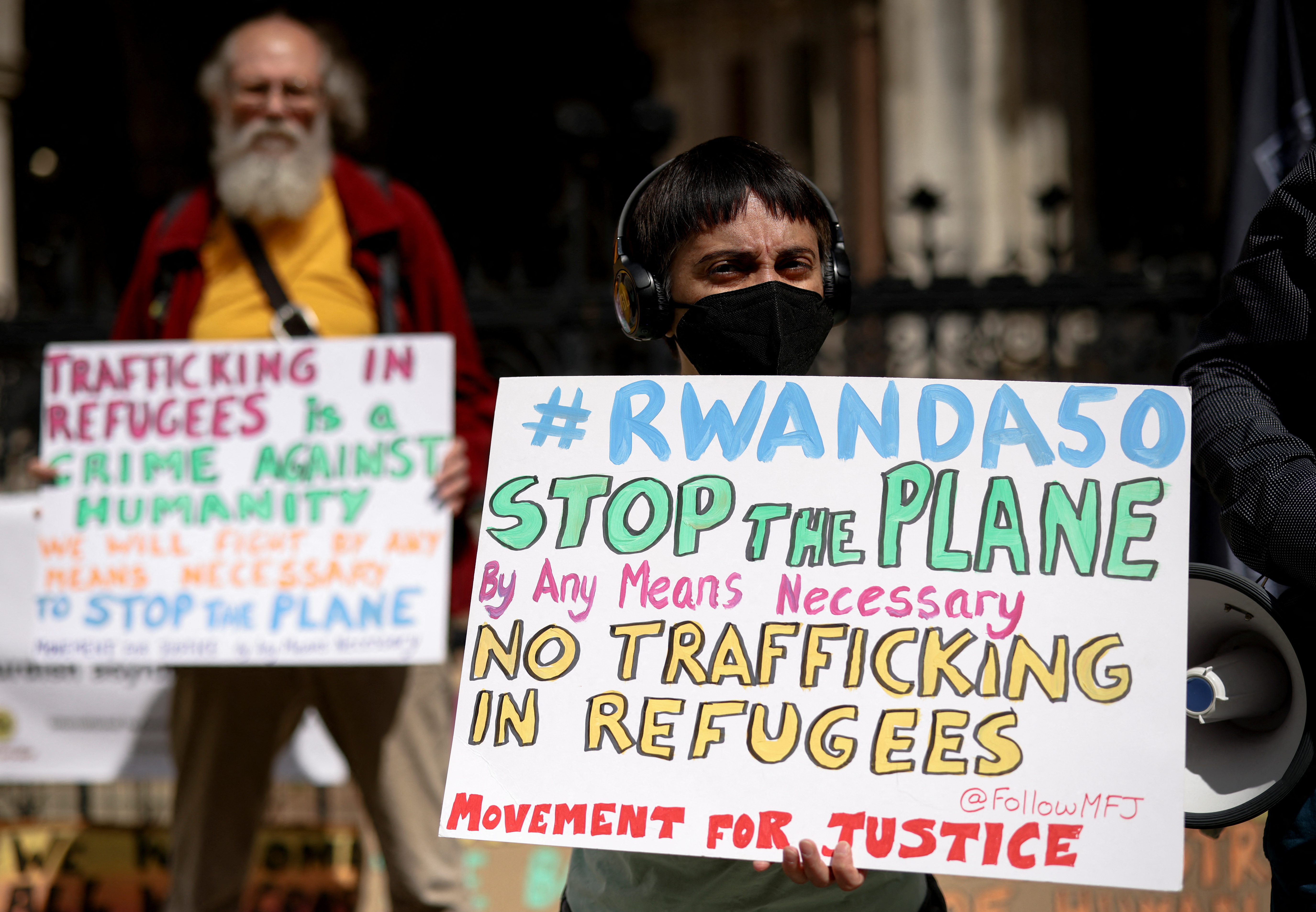 Demonstrators display placards during a protest outside the Royal Courts of Justice whilst a legal case is heard over halting a planned deportation of asylum seekers from Britain to Rwanda