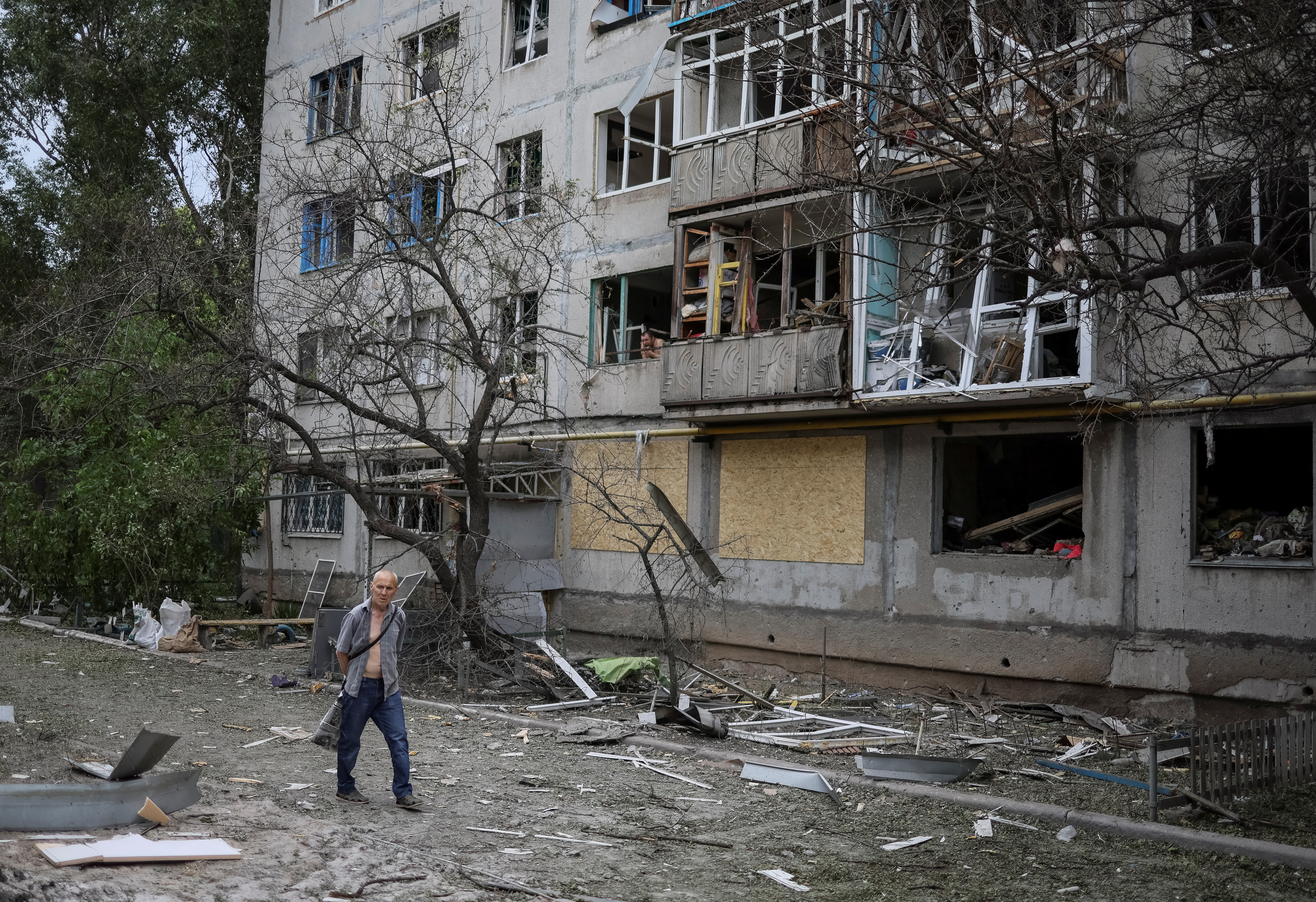 A resident walks by a damaged apartment building in Ukraine