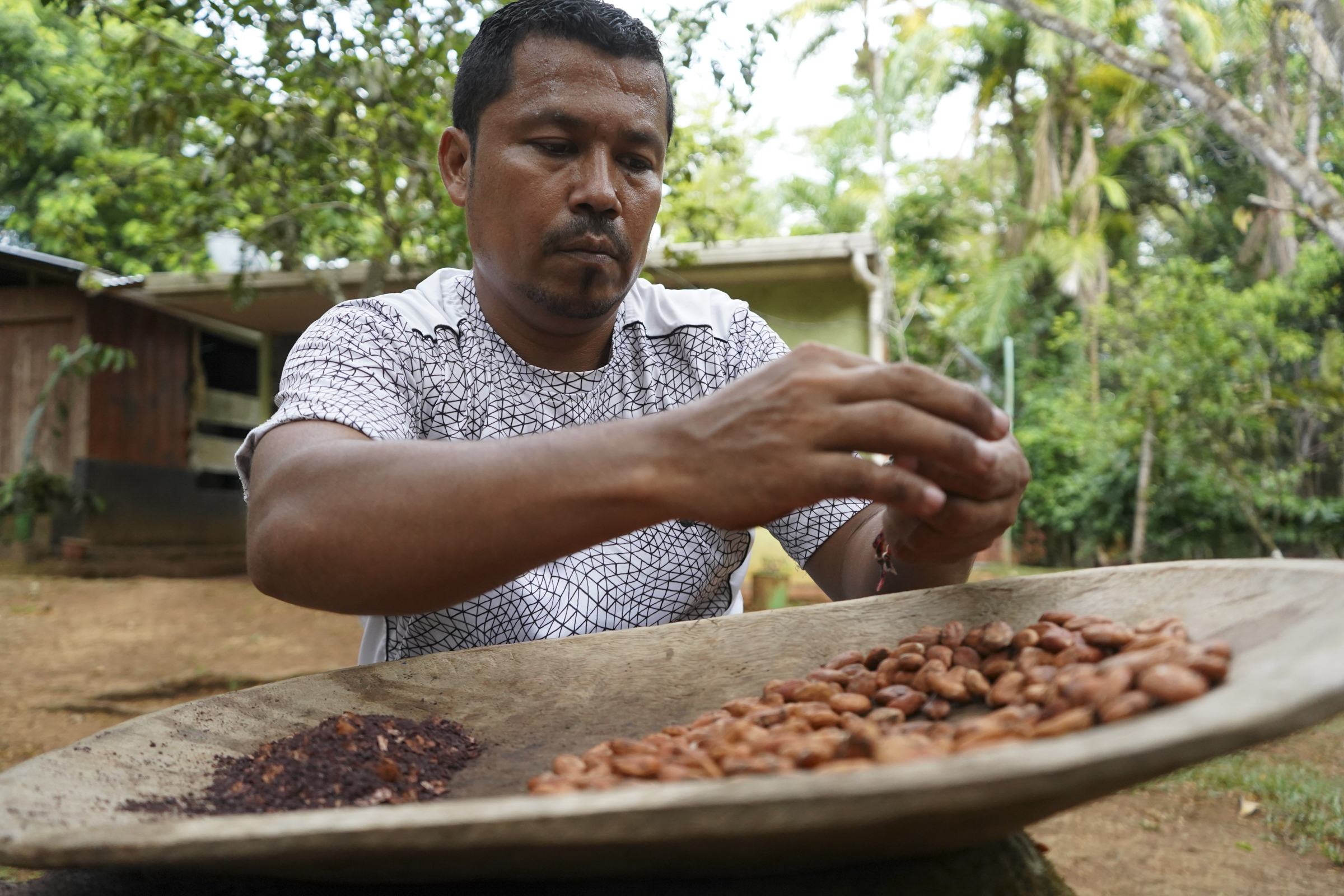 A photo of Jeffrey Villanueva, 44, crushing cocoa beans at his family home.