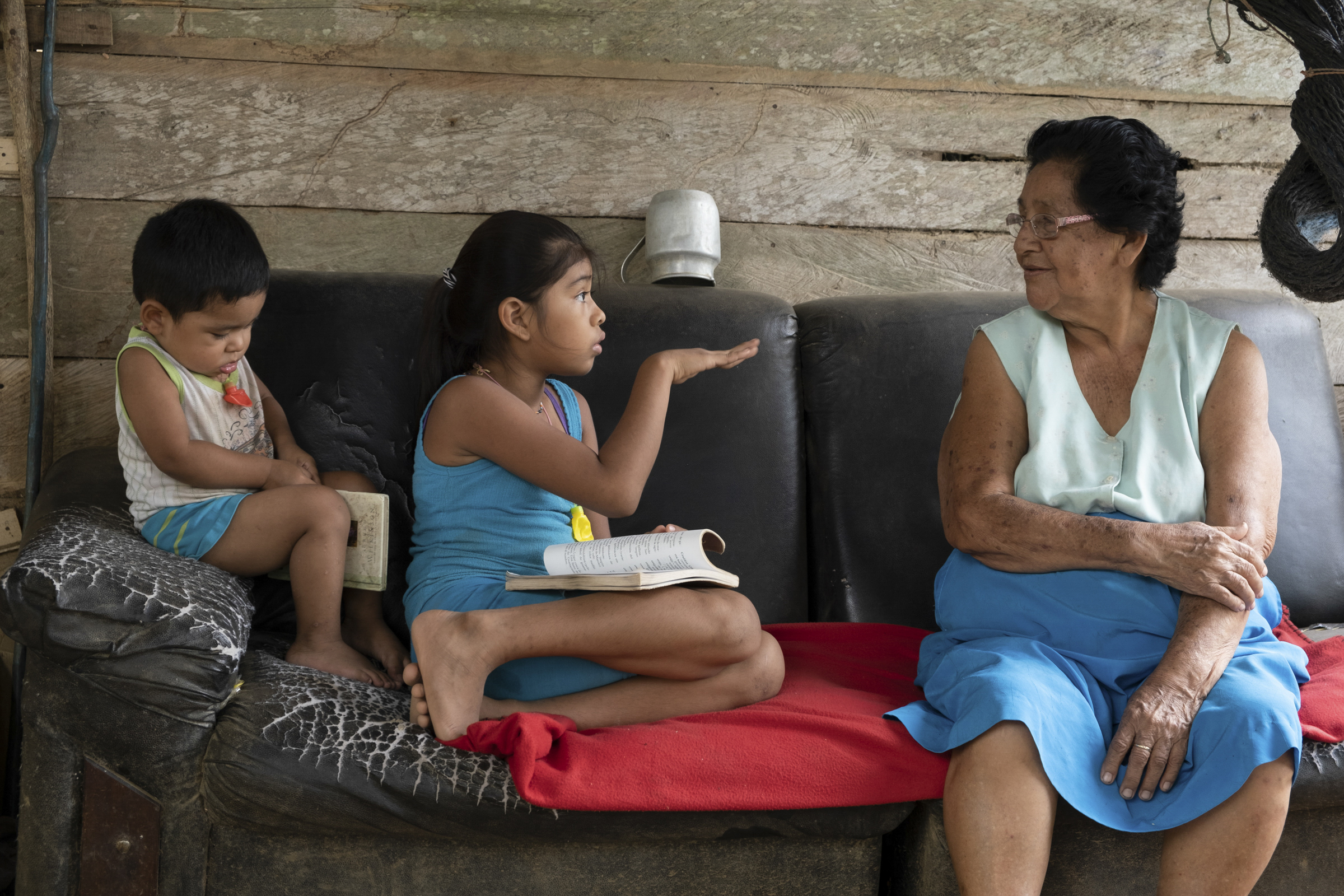 A photo of Celedina Moroto with two of her grandchildren sitting next to her on a sofa.