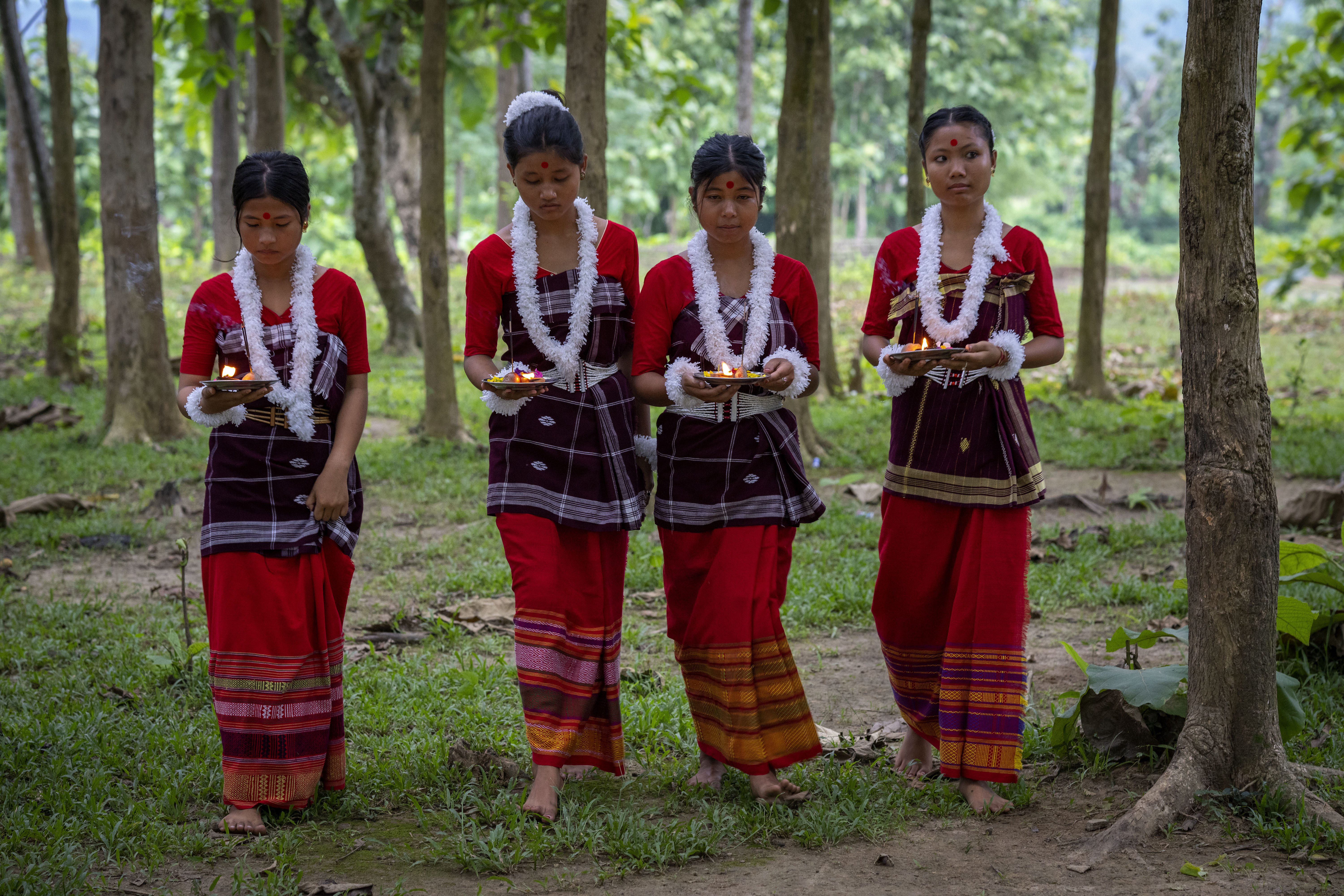 Indian Rabha tribal girls in traditional attire bring offerings before they perform a tribal Rabha dance