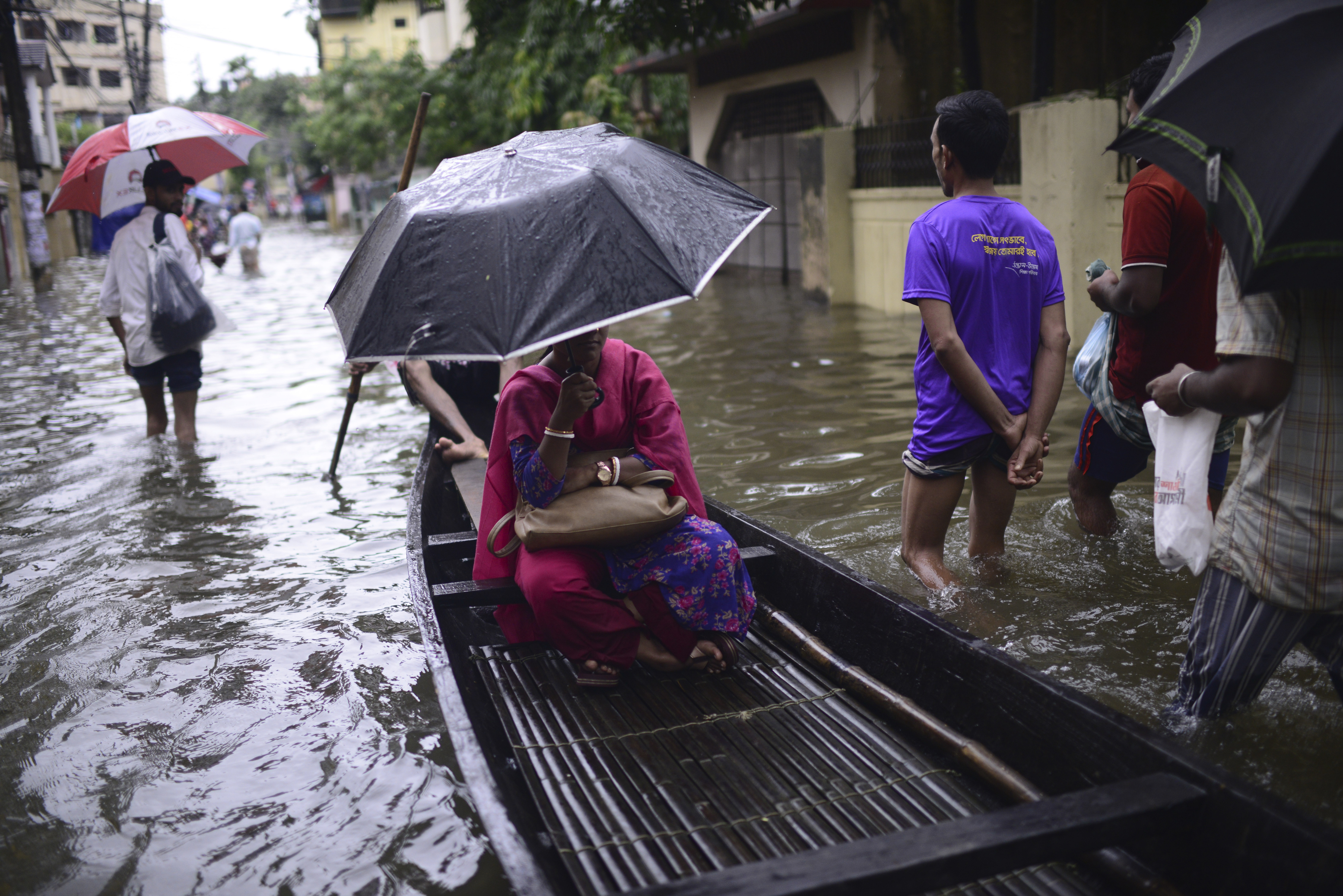 A woman sits in a country boat as it moves through flood waters in Sylhet