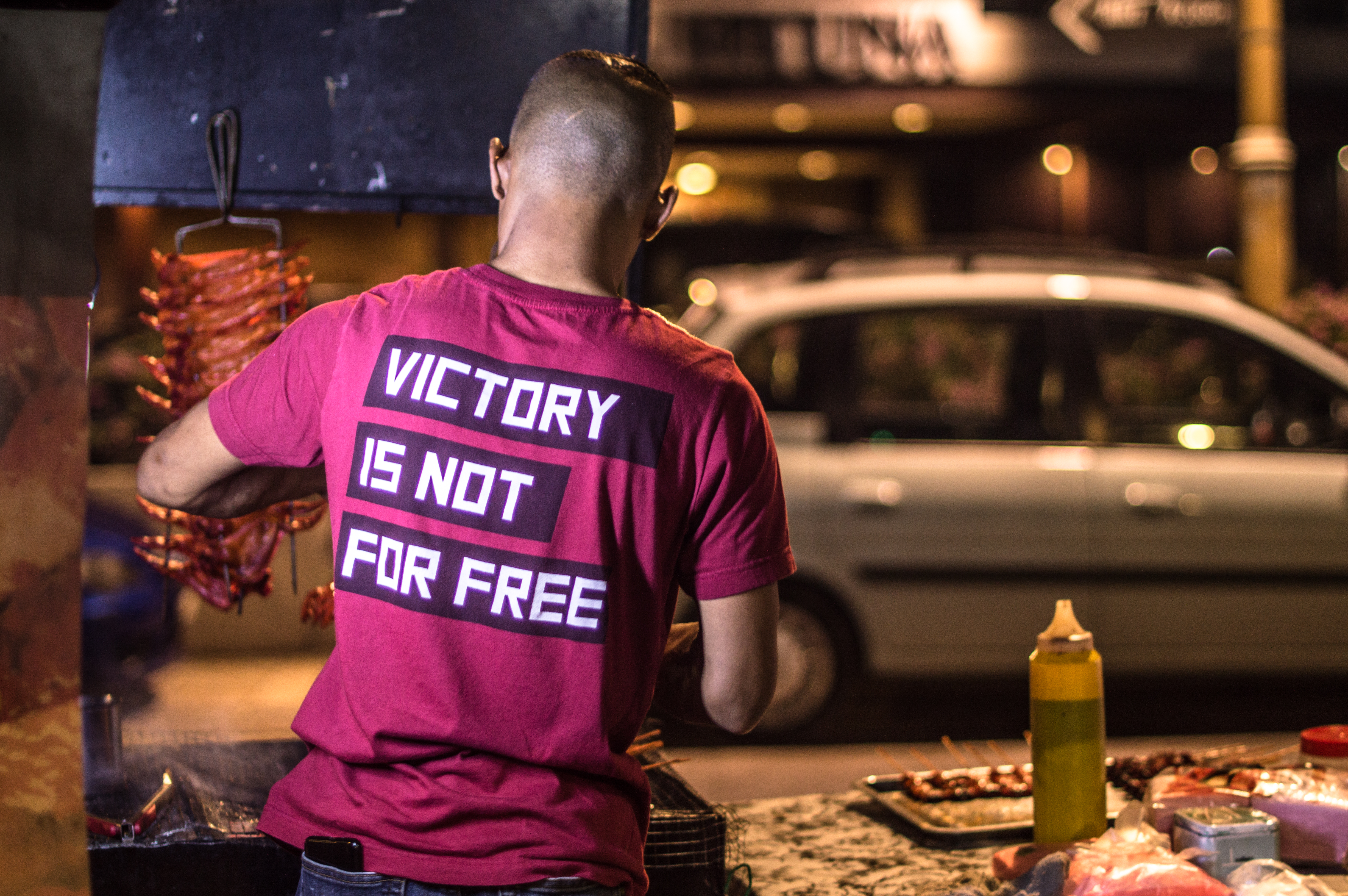 A hawker with his back to the camera preparing food at a stall in the Bukit Bintang area of Kuala Lumpur, Malaysia.