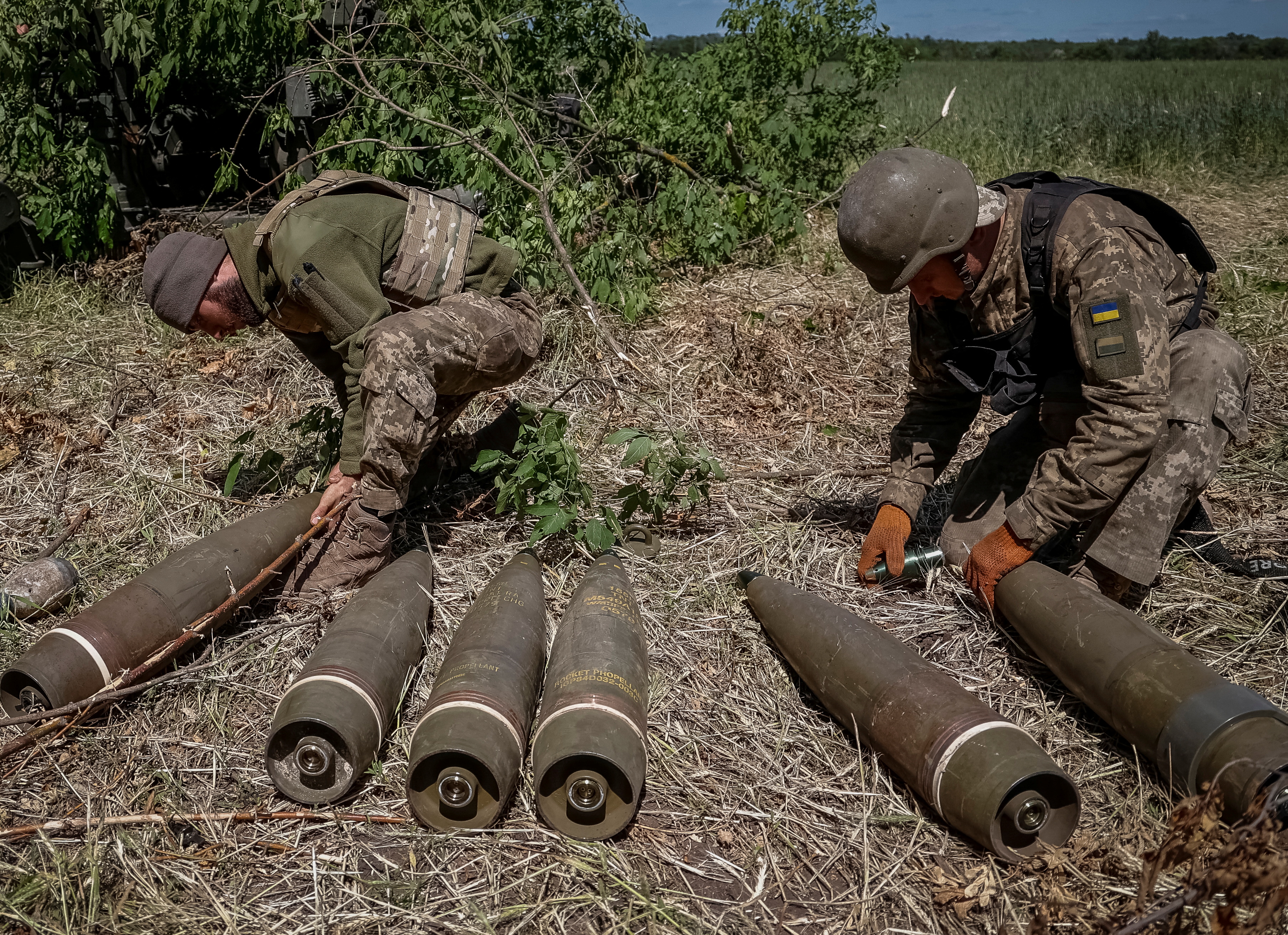 A photo of Ukrainian service members preparing shells for a M777 Howitzer near a frontline.