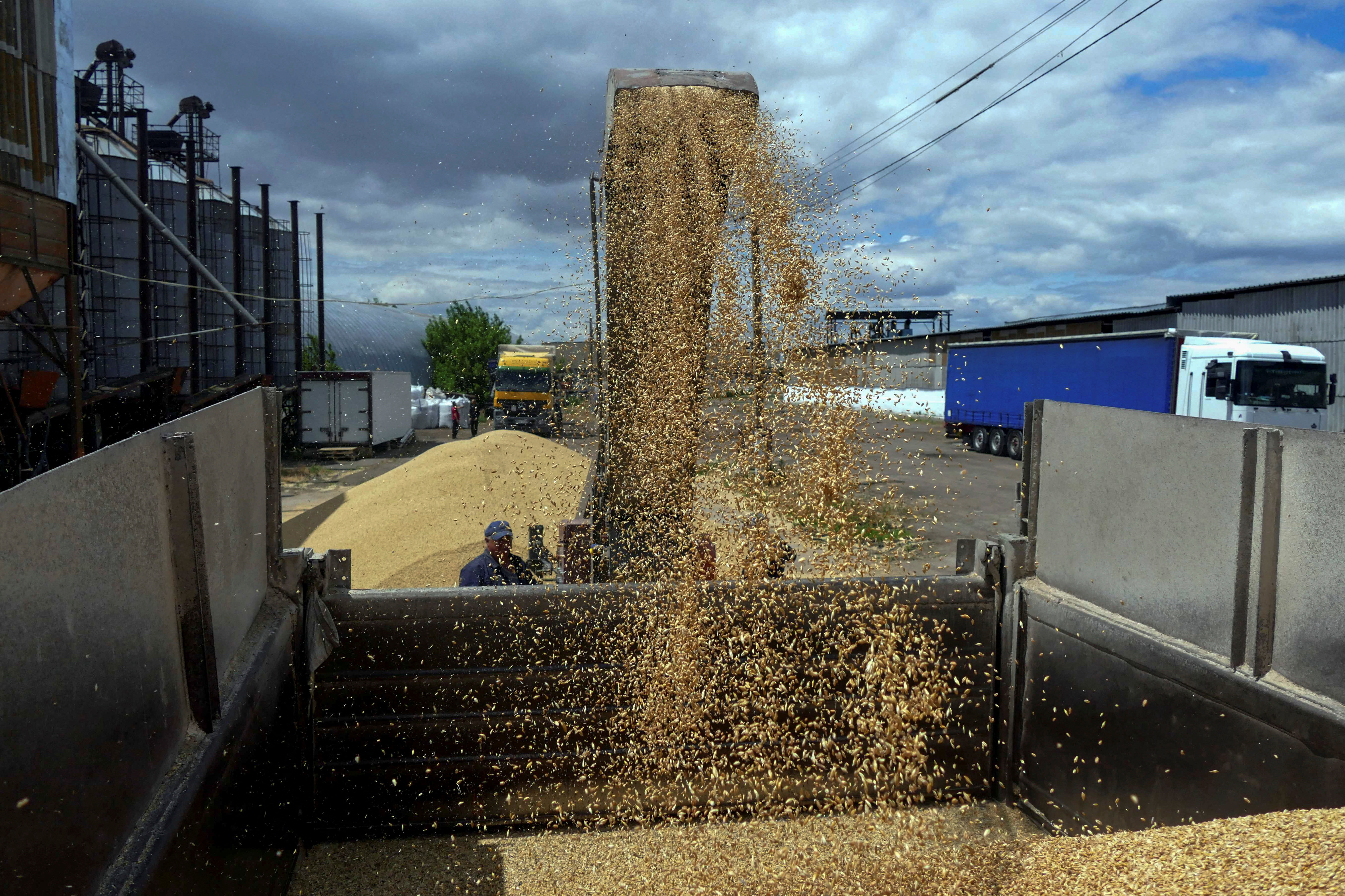 A photo of a worker loading a truck with grain.