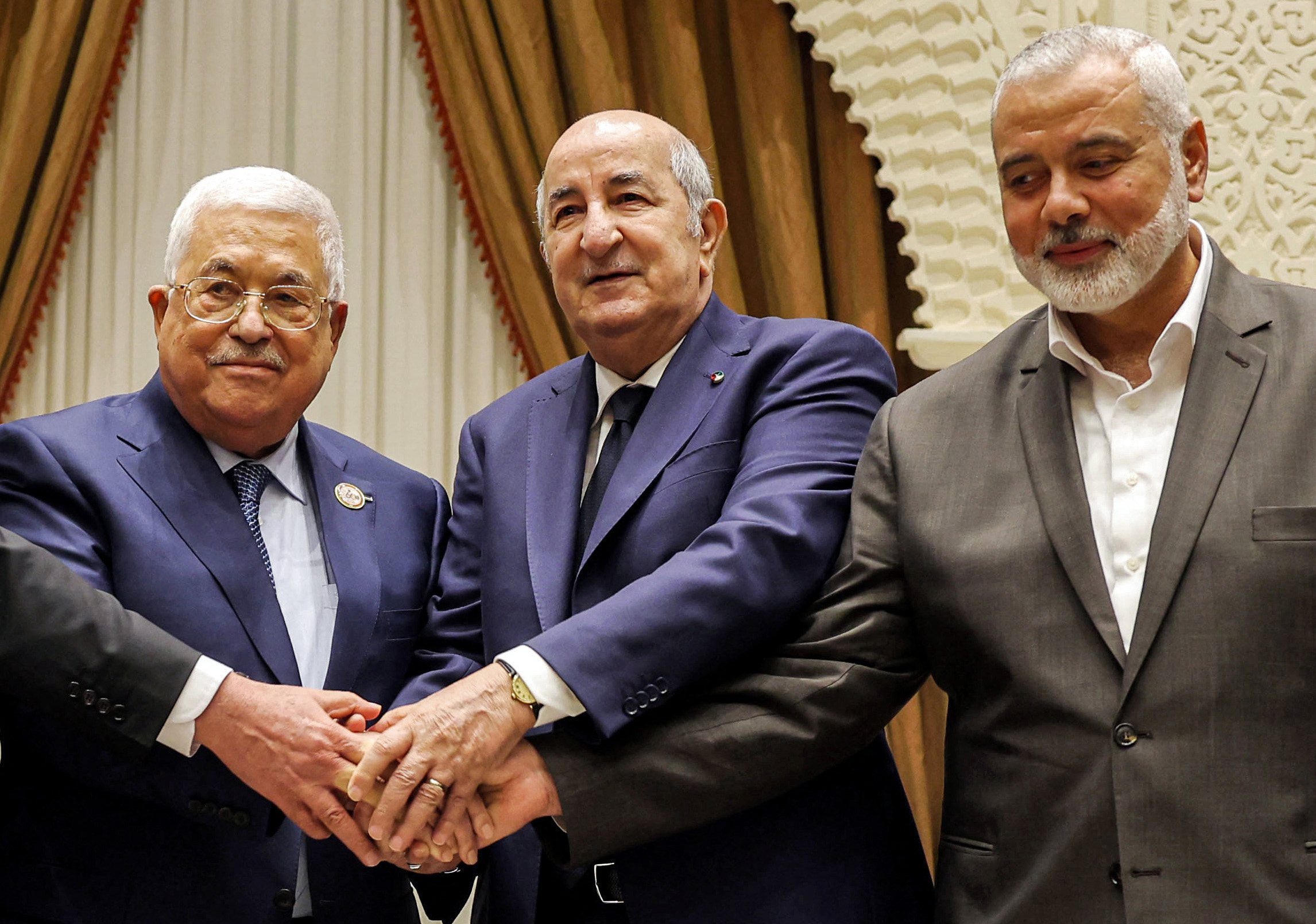 An alternative crop of a handout picture provided by the Palestinian Authority's press office (PPO) on July 5, 2022 shows (L to R) Palestinian president Mahmud Abbas shaking hands with Algerian President Abdelmajid Tebboune and with Palestinian Hamas movement's leader Ismail Haniyeh during Abbas' visit to attend Algeria's 60th independence anniversary in the capital Algiers. - Palestinian president Mahmud Abbas and Hamas leader Ismail Haniyeh met publicly for the first time in over five years